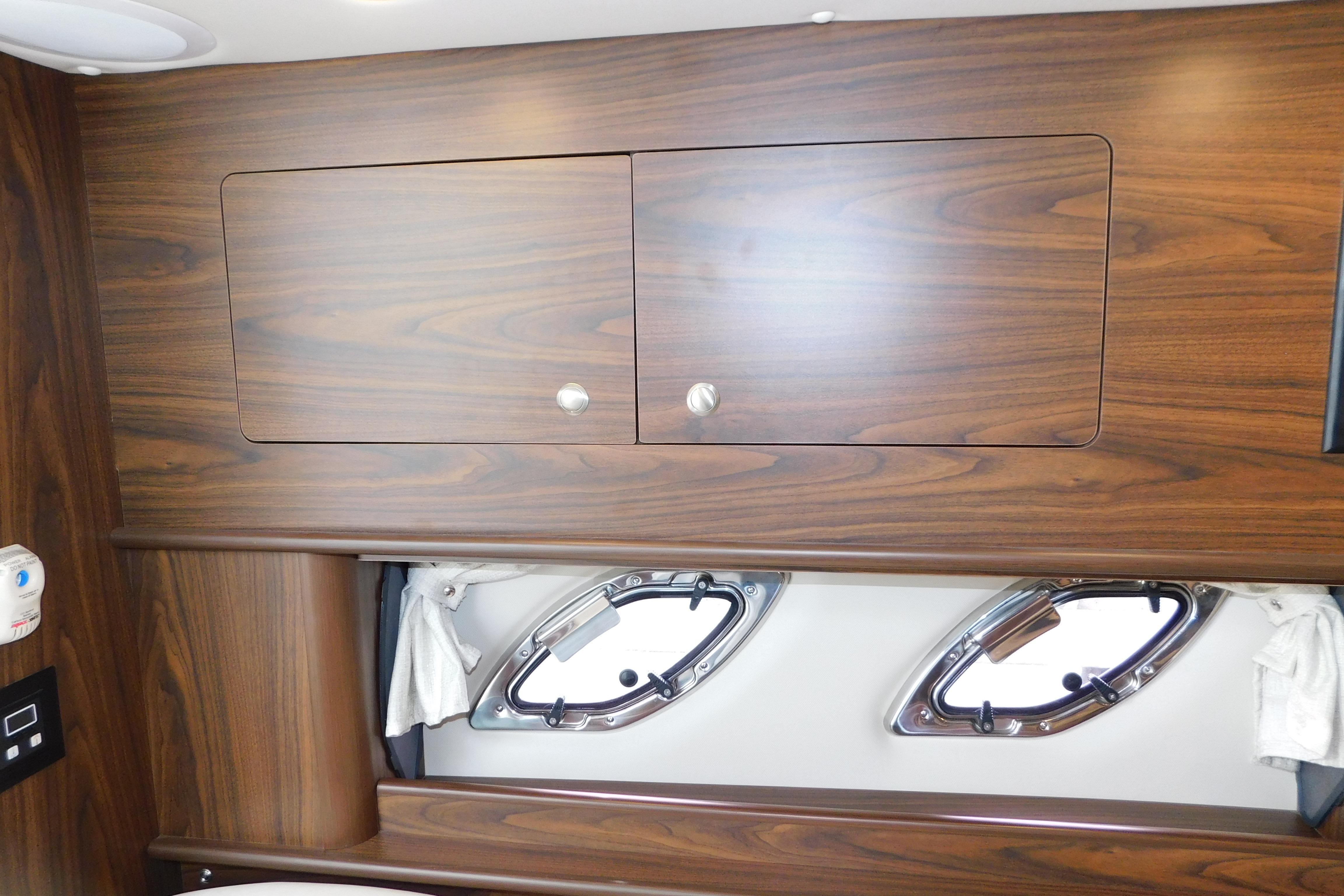 Wooden interior cabinetry and portholes in a 2017 Rinker EX 320 boat cabin.