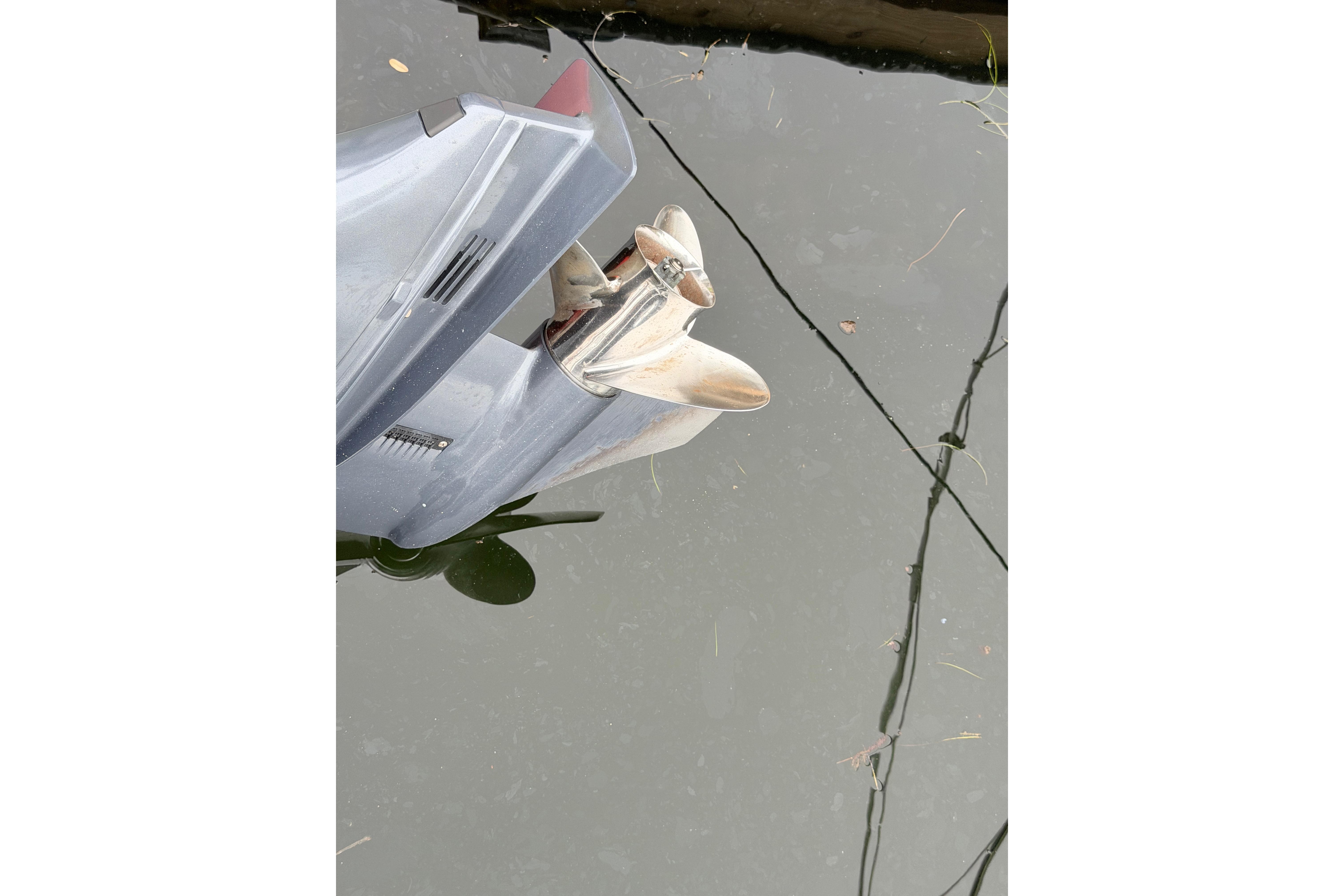 Outboard motor of a 2019 World Cat 230 DC boat partially submerged in water.