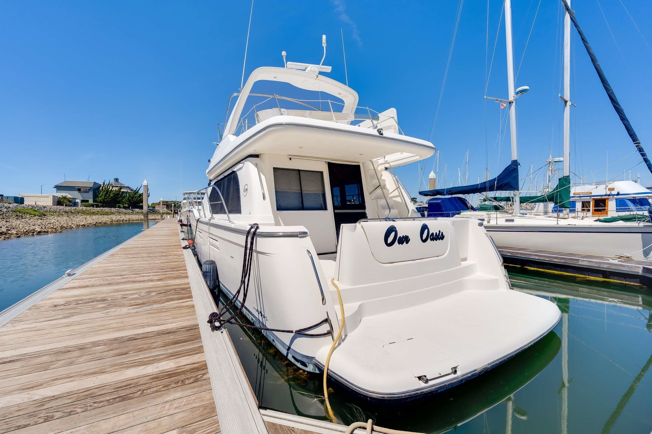 1998 Bayliner 5788 Pilot House Motoryacht docked at marina under clear blue sky.