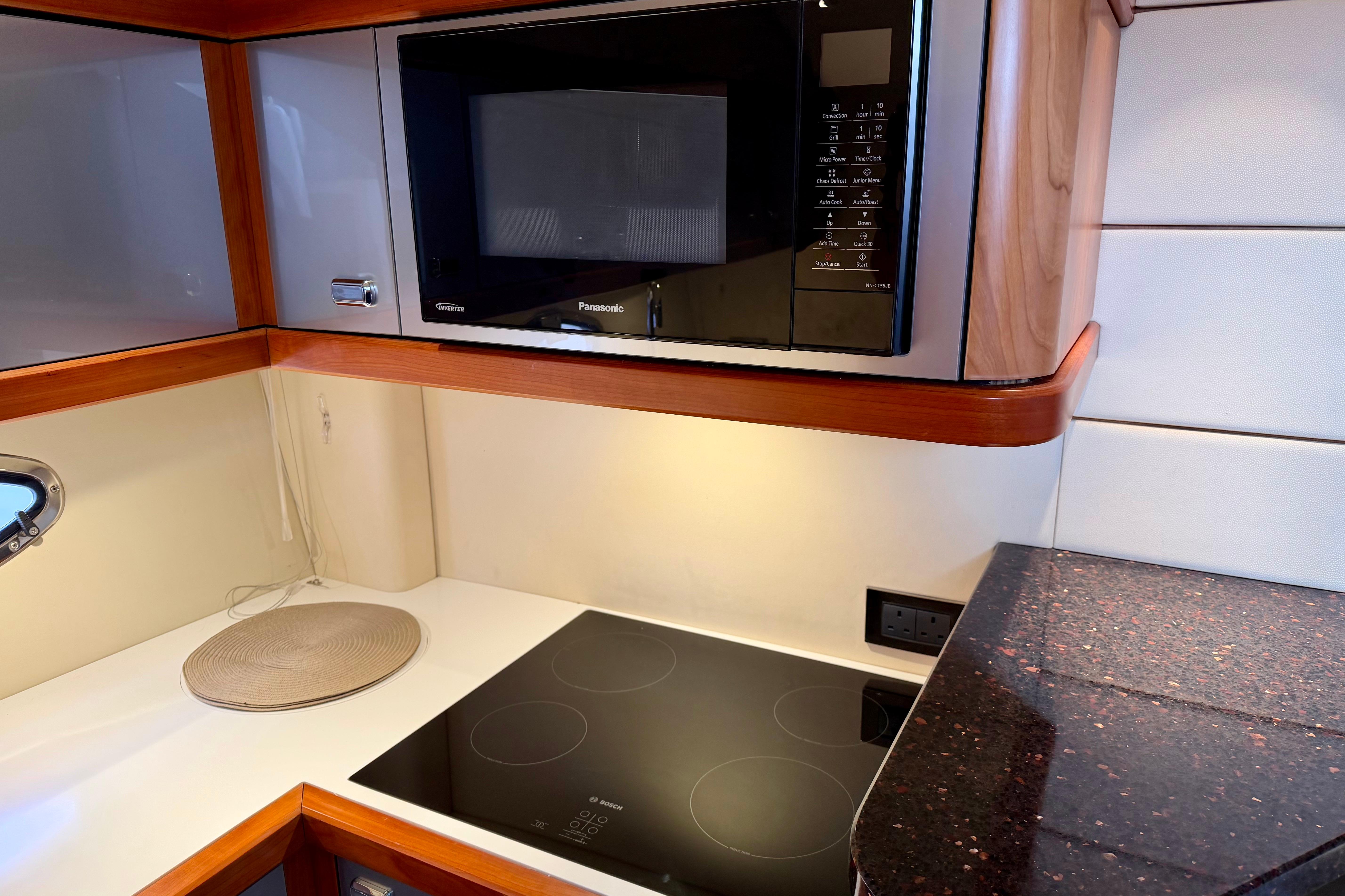 Modern kitchen area in a 2007 Sunseeker Portofino 47 yacht with microwave and stovetop.