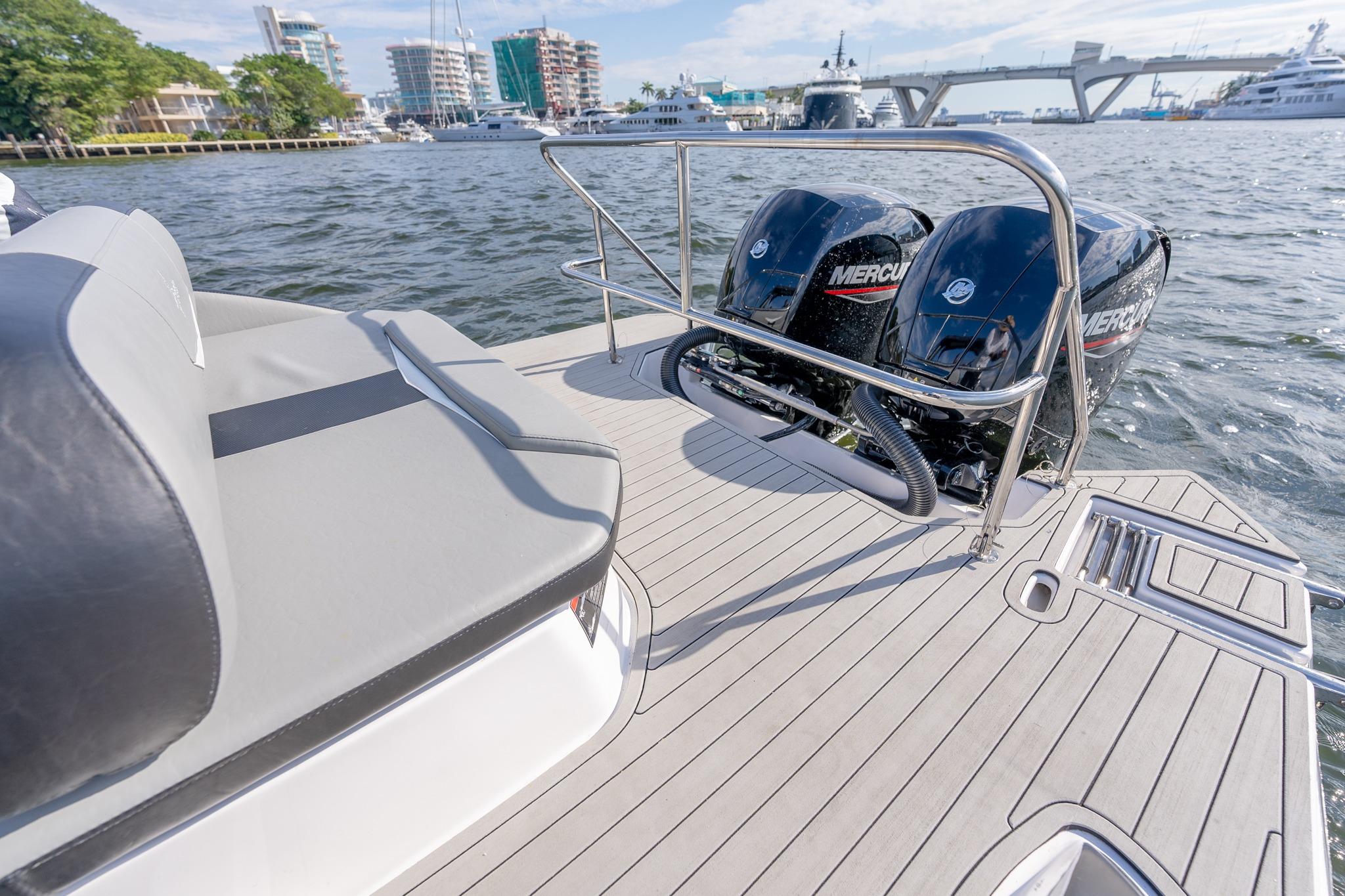 Luxury Hanover 305 boat deck with twin Mercury engines, docked near waterfront buildings, 2027 model.