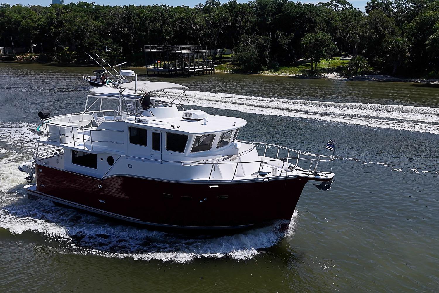 A 2003 Magna Marine Nova Scotia 47 yacht cruising on a scenic river.