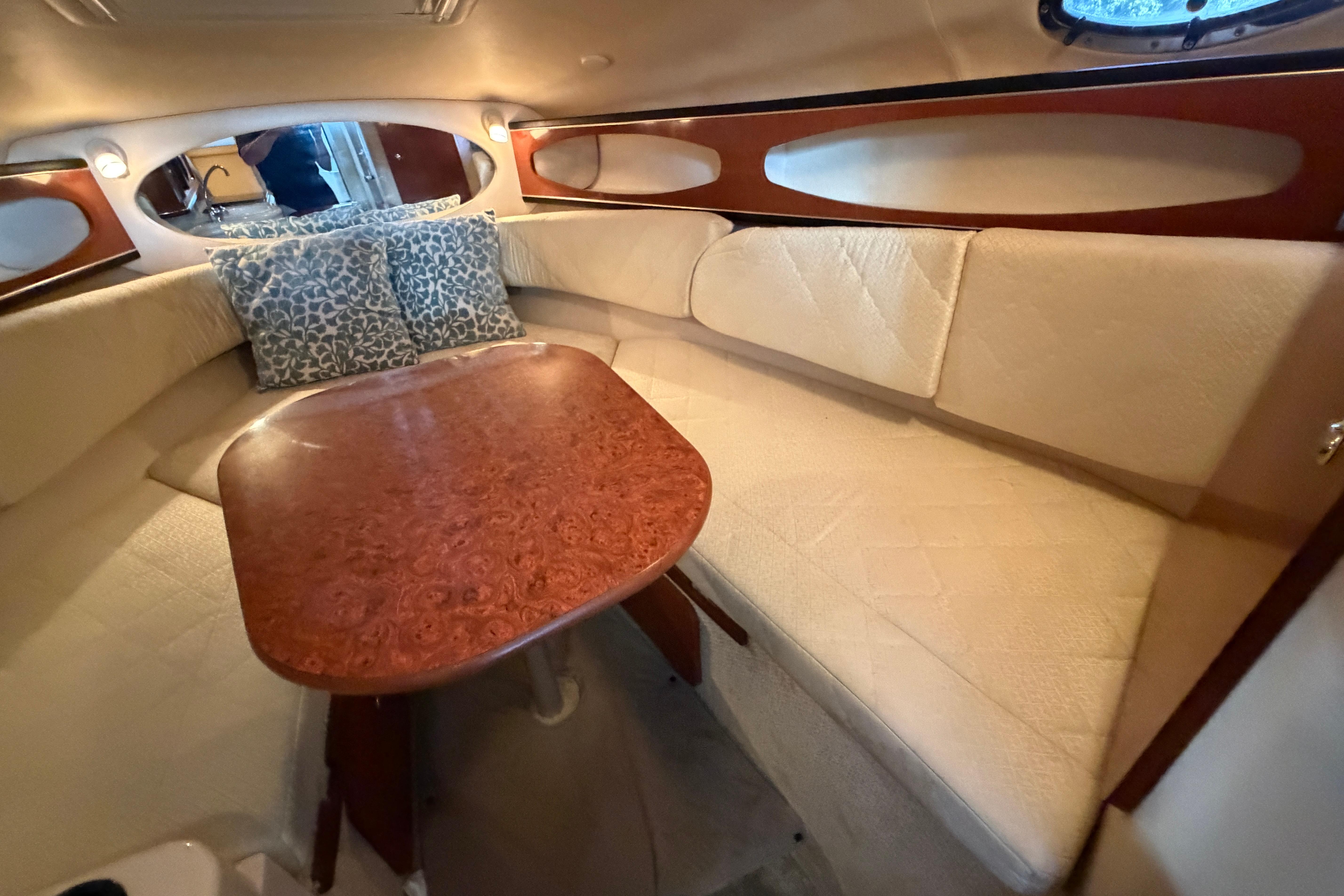 Interior of 2004 Sea Ray Sundancer 260 with cozy seating and elegant wood table.