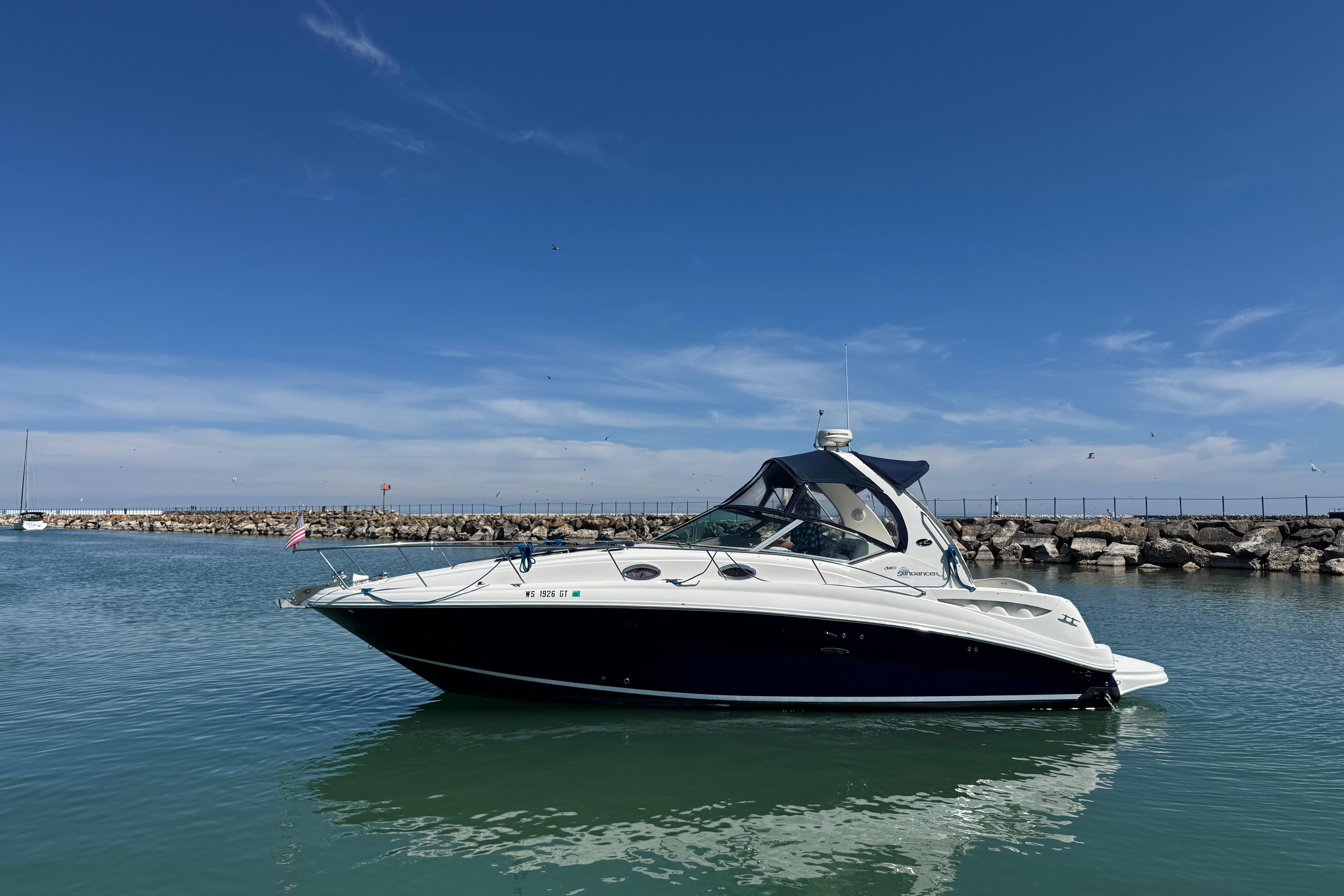 2004 Sea Ray Sundancer 320 yacht on calm water under clear blue sky.