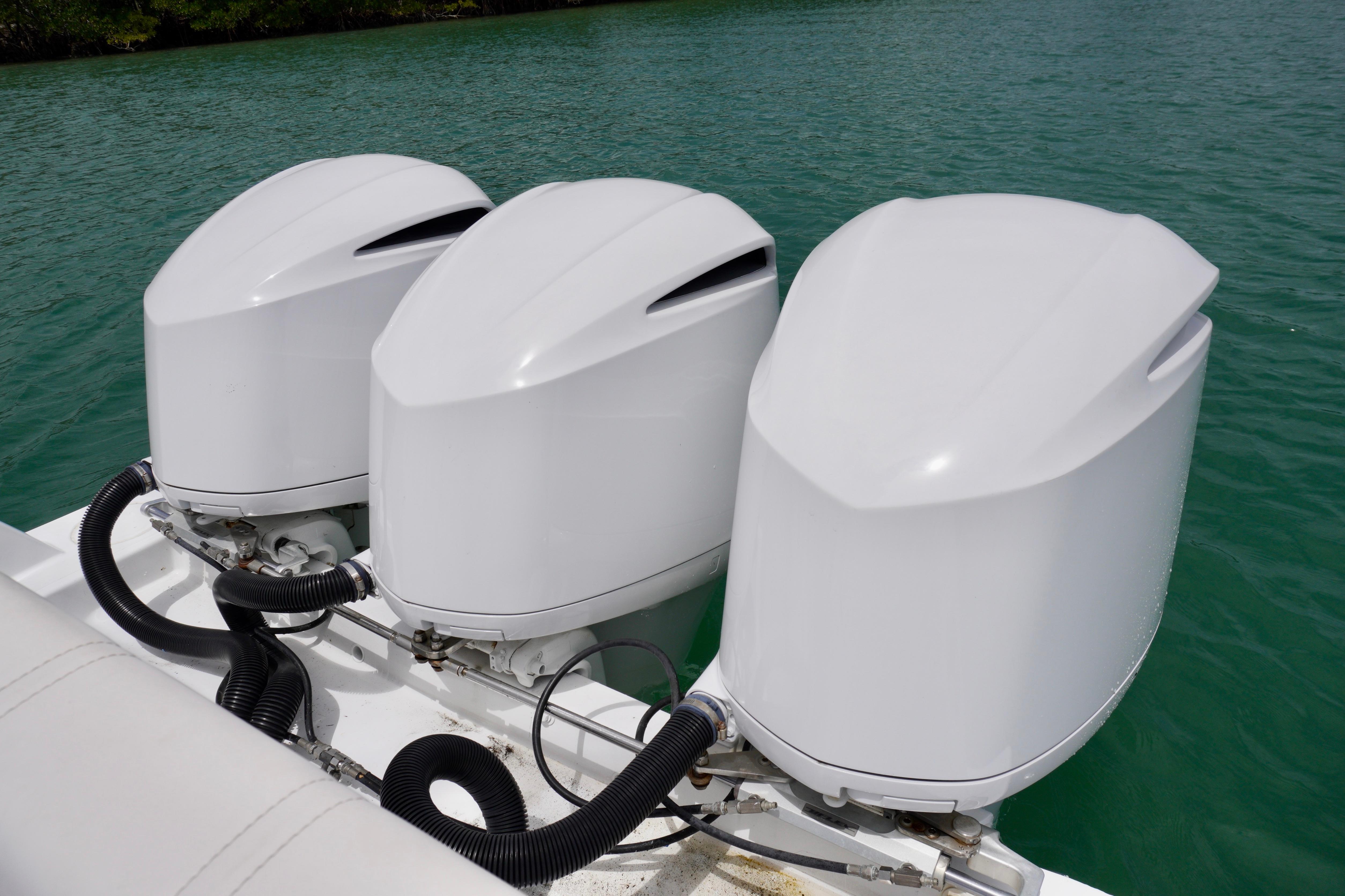 Triple outboard motors on a 2013 Contender 35 LS boat in clear water.
