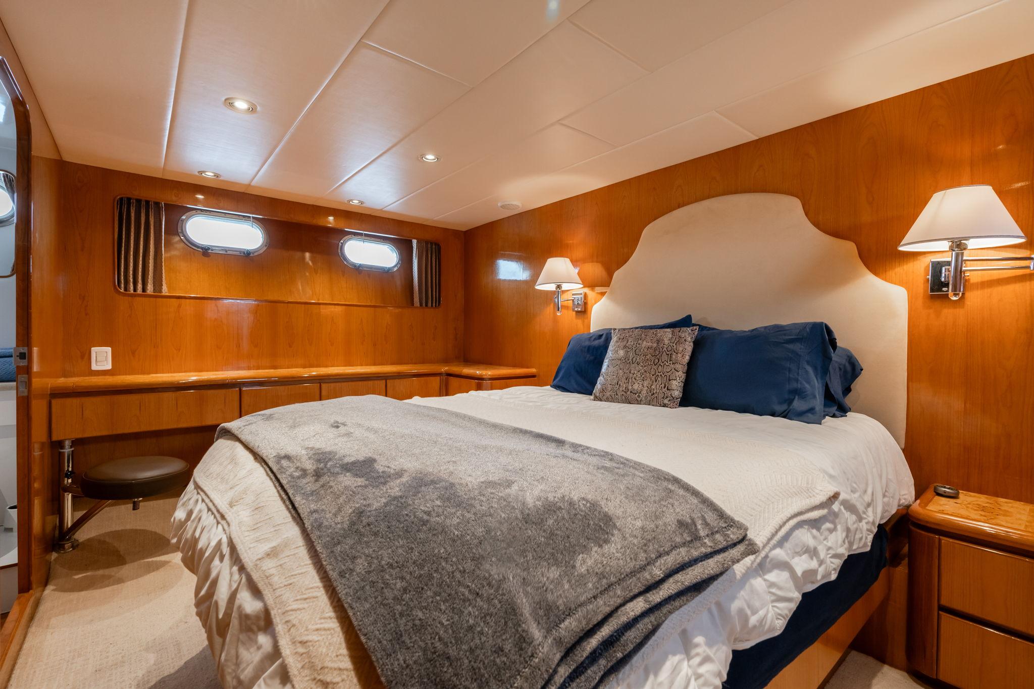 Luxurious bedroom in 1999 Vitech 68' Pilothouse yacht with elegant wood paneling and cozy bedding.