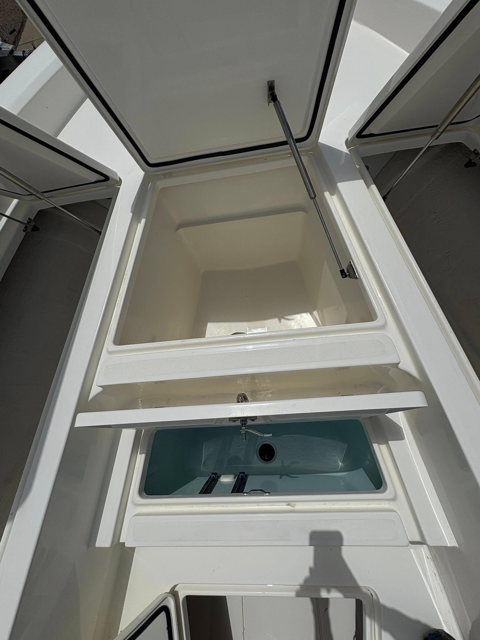 Open storage compartments on a 2025 Mako 24 APEX boat, showcasing interior space.