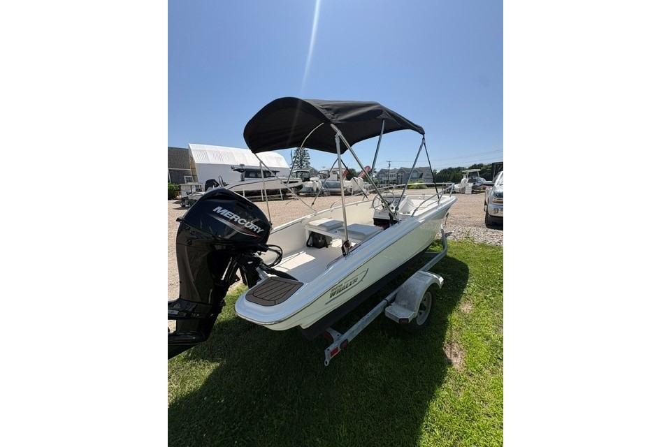 2024 Boston Whaler 130 Super Sport boat with canopy on trailer, sunny day.