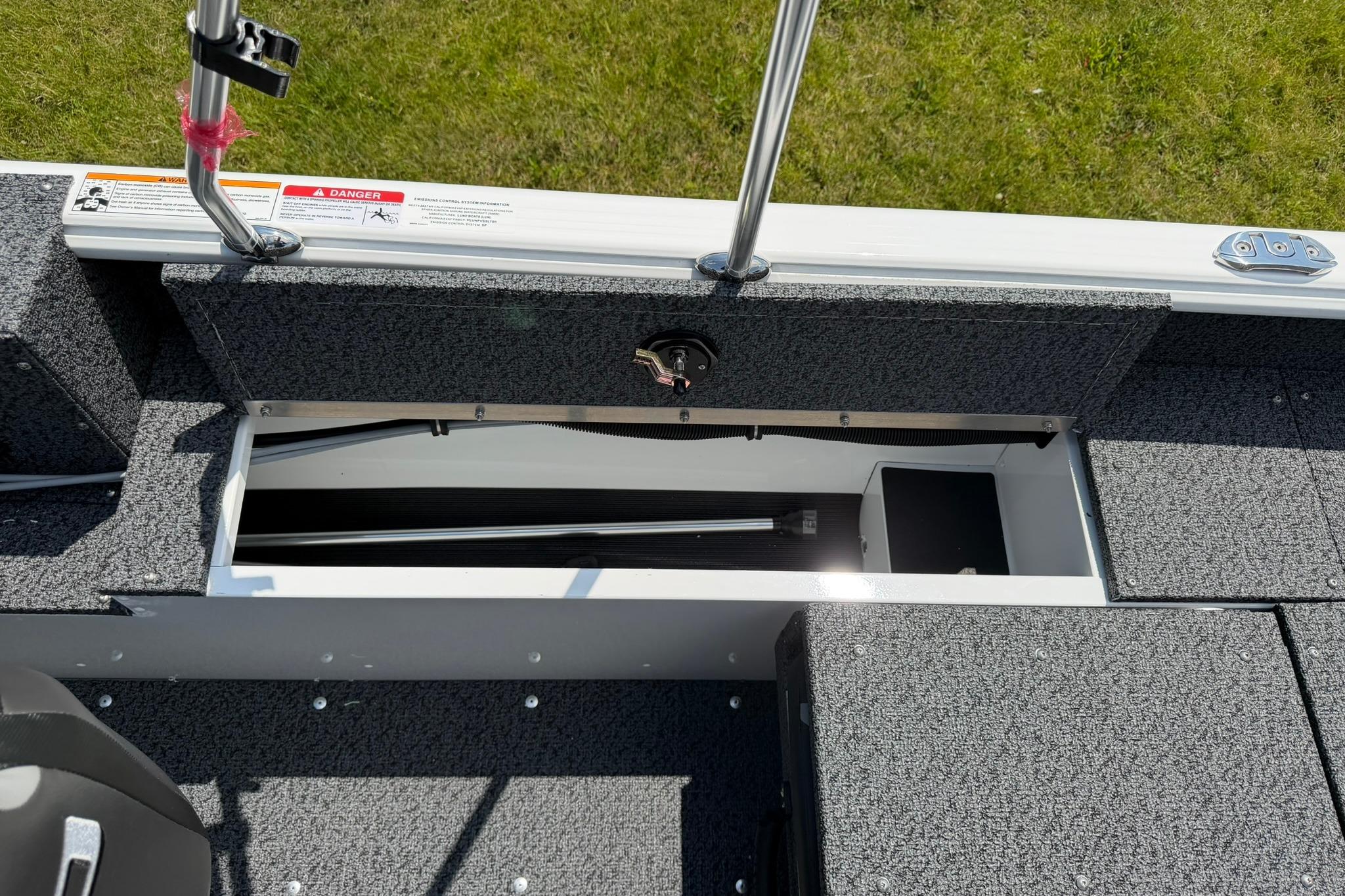 Open storage compartment on 2027 Lund 1675 Adventure Sport boat, featuring gray carpeted interior.