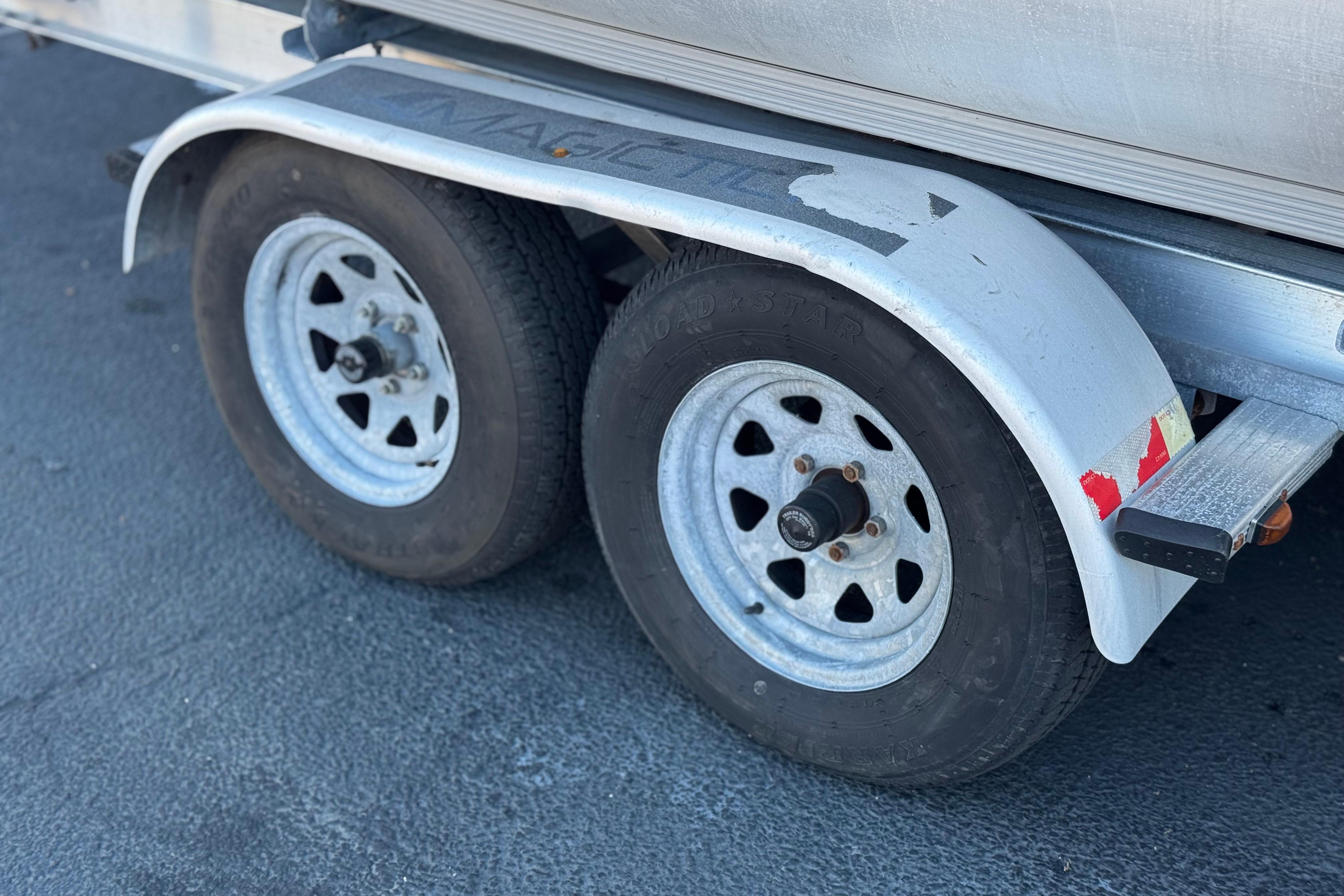 Trailer wheels of a 2013 Bennington 2575QCW I/O boat on pavement.