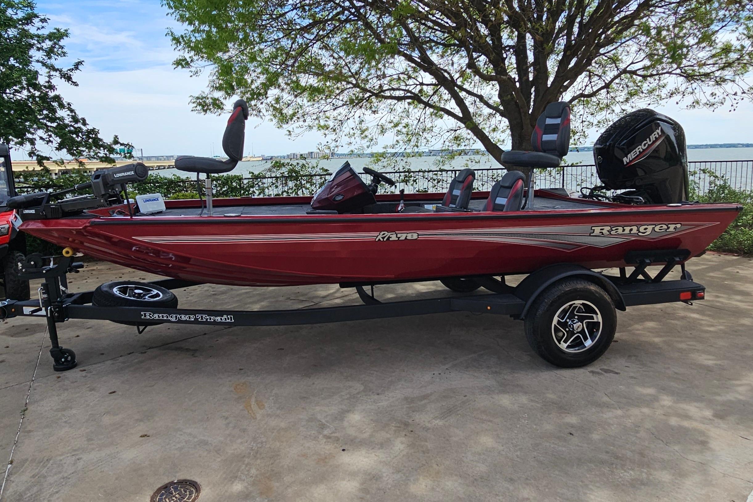 2026 Ranger RT178 boat in red on a trailer, parked near a scenic waterfront.