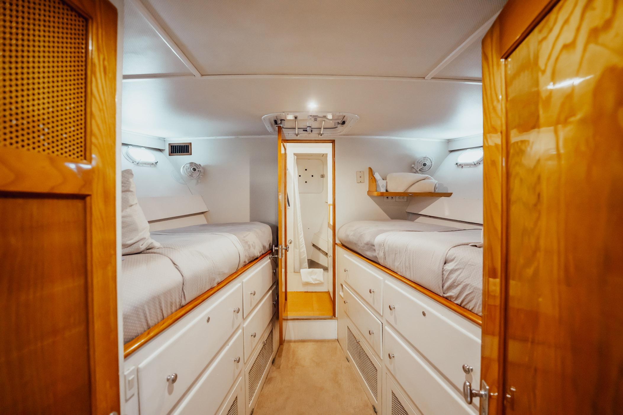 Interior of 1972 Trumpy 72 Motor Yacht with twin beds and wooden cabinetry.