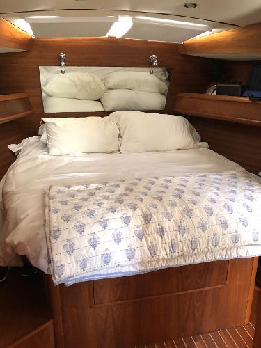 Cozy cabin interior of 2001 Jeanneau 45.2 sailboat with wooden finish and comfortable bedding.
