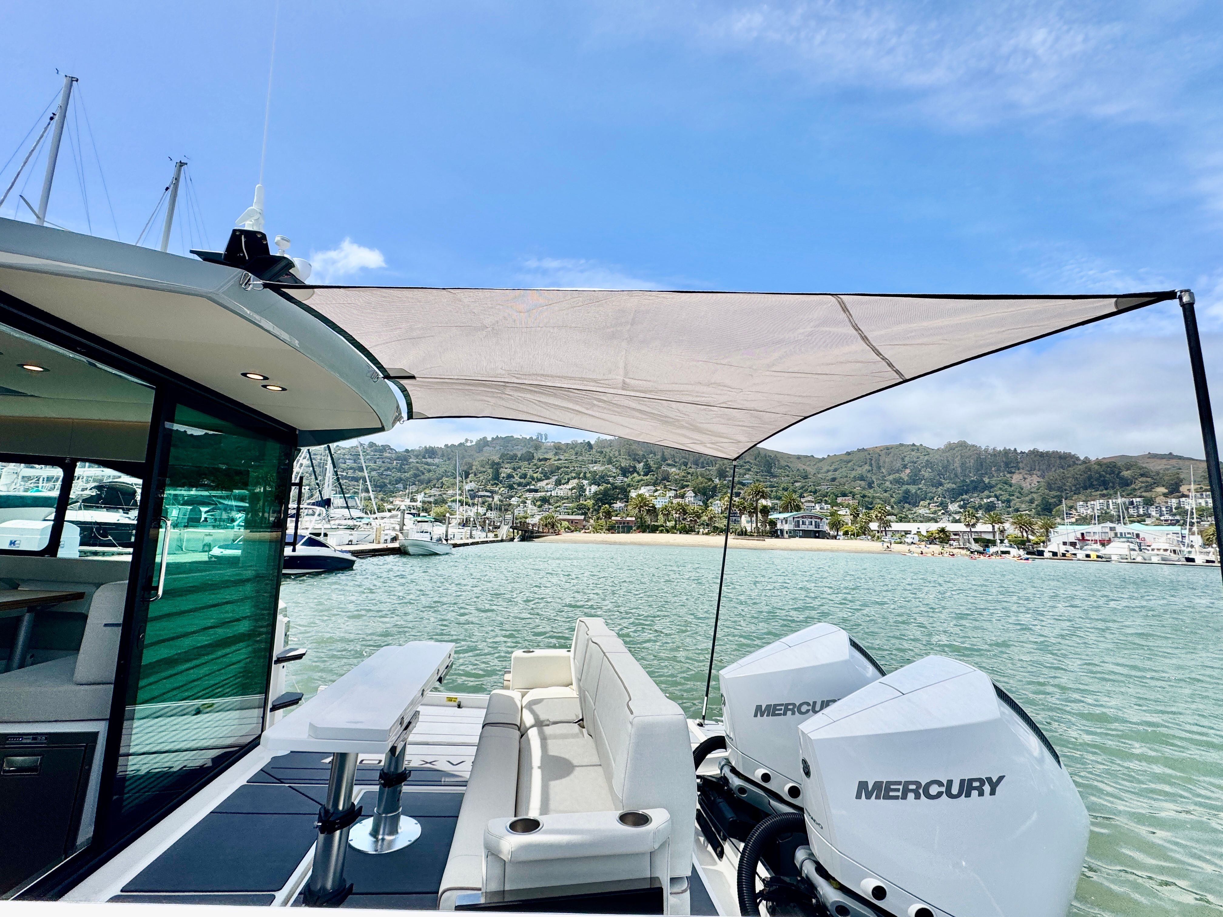 The 2025 Saxdor 320 GTC is on the water with two Mercury engines and a sunshade.