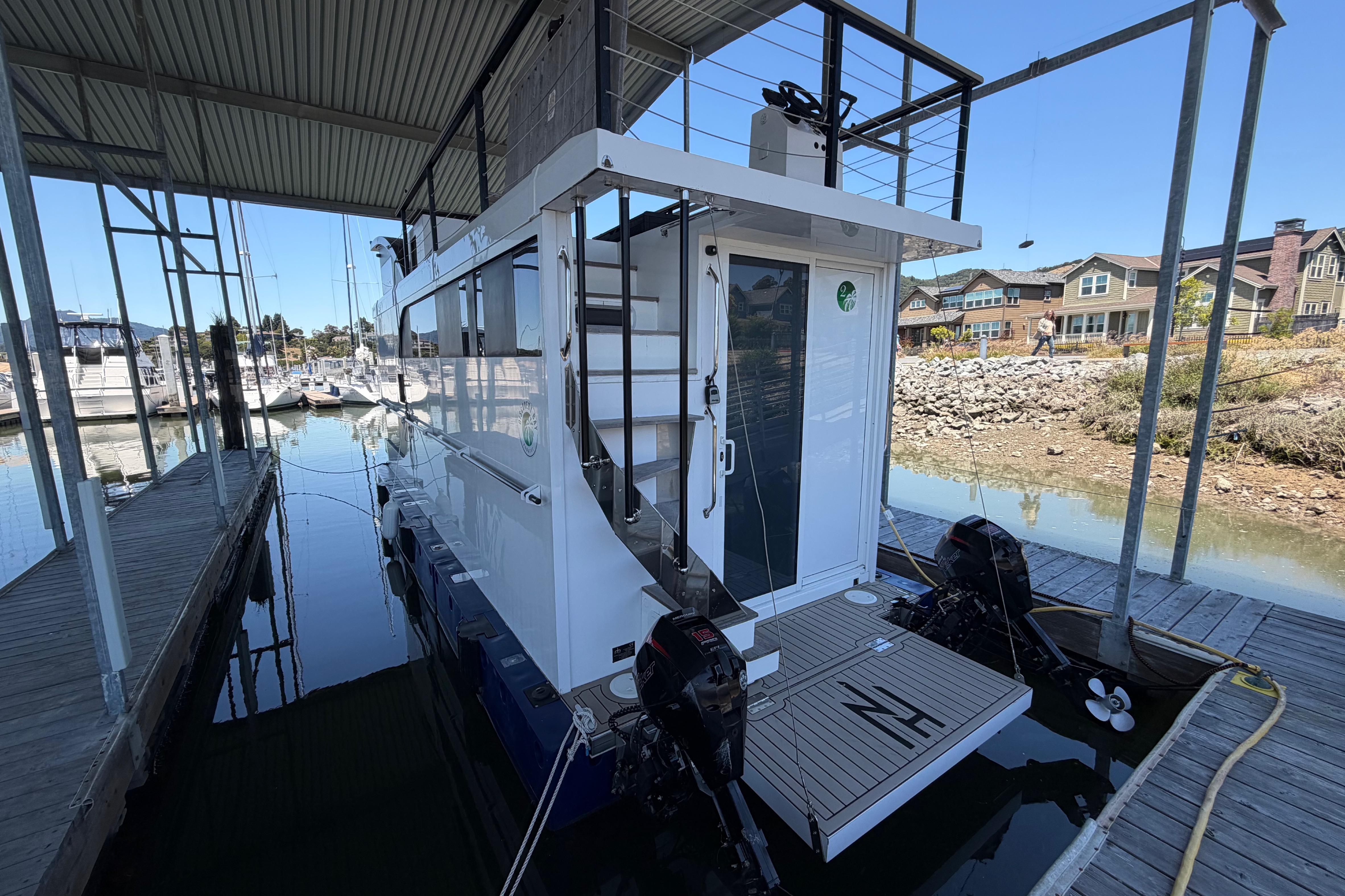Modern 2022 Navisyo NV.08 houseboat docked in a marina, showcasing sleek design and dual outboard motors.