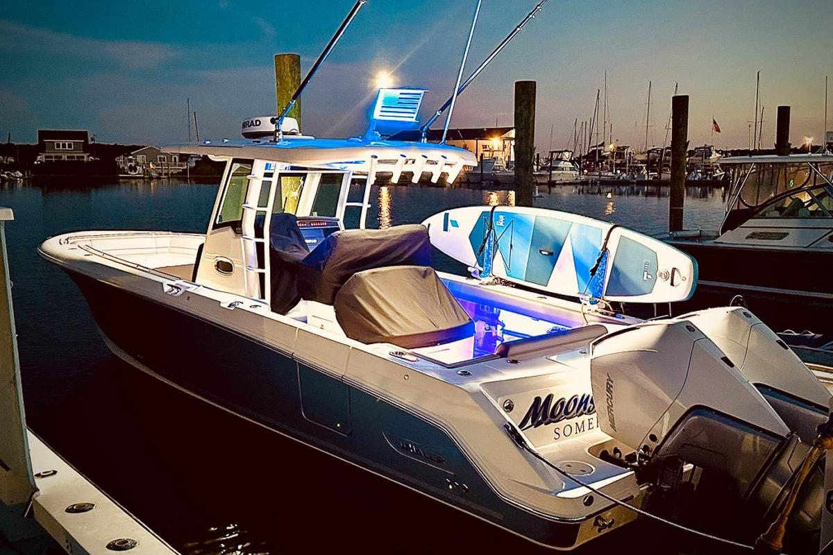 2023 Boston Whaler 330 Outrage docked at sunset with paddleboards.