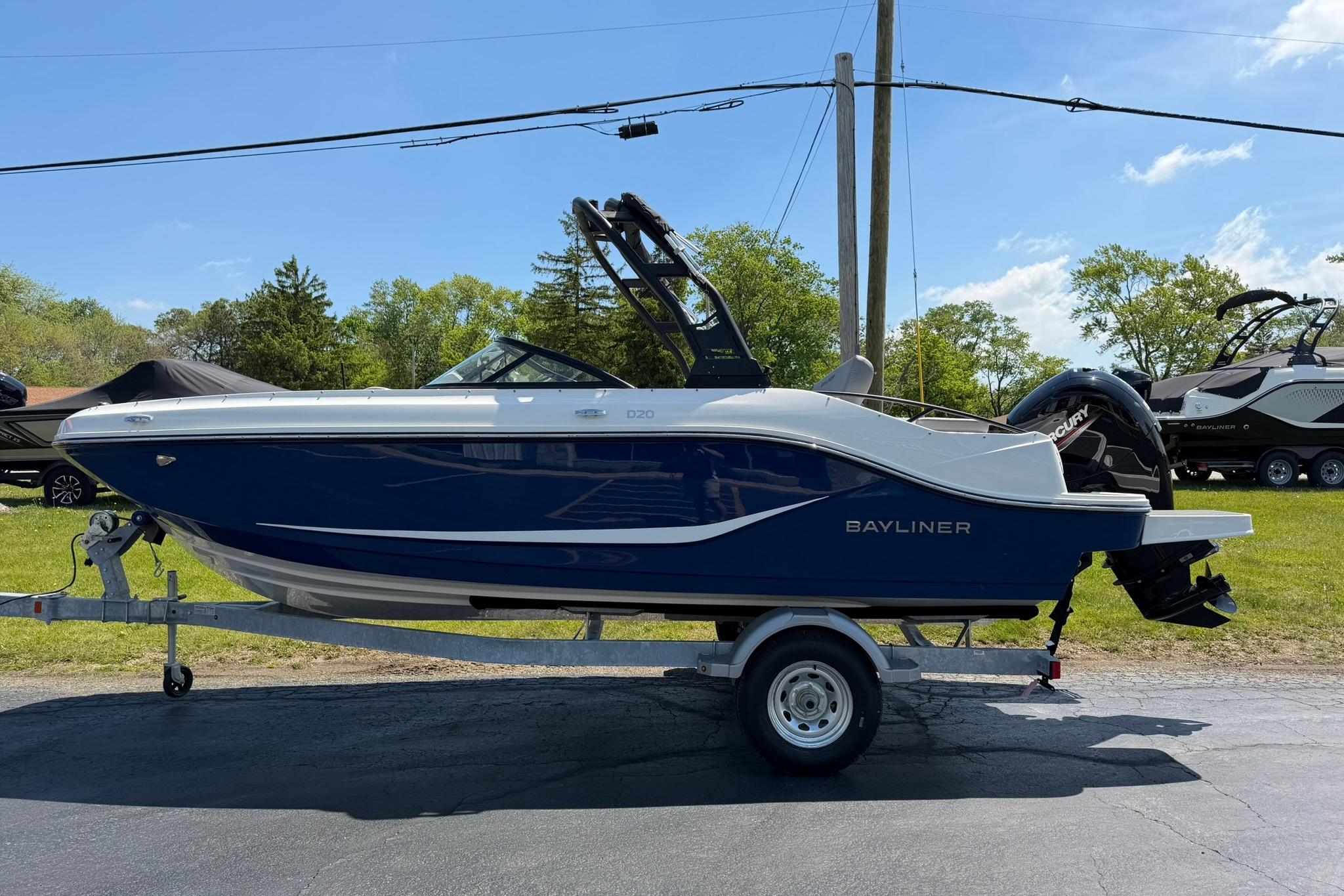 2026 Bayliner D20 boat on trailer, parked outdoors under clear blue sky.