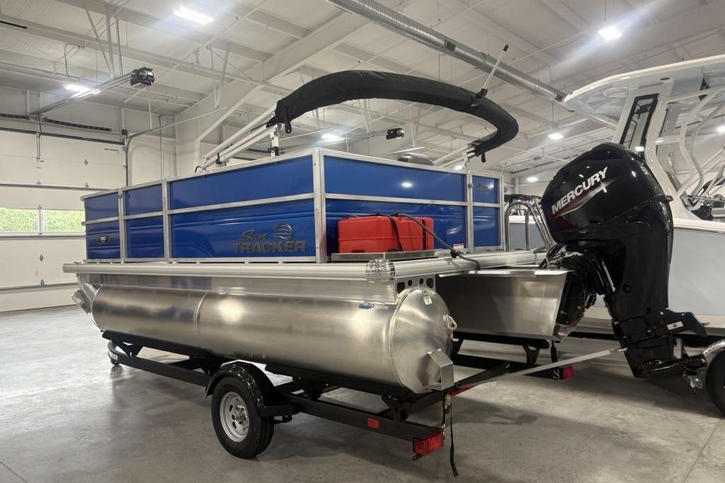 2026 Sun Tracker Party Barge 16 DLX pontoon boat with Mercury outboard motor in showroom.