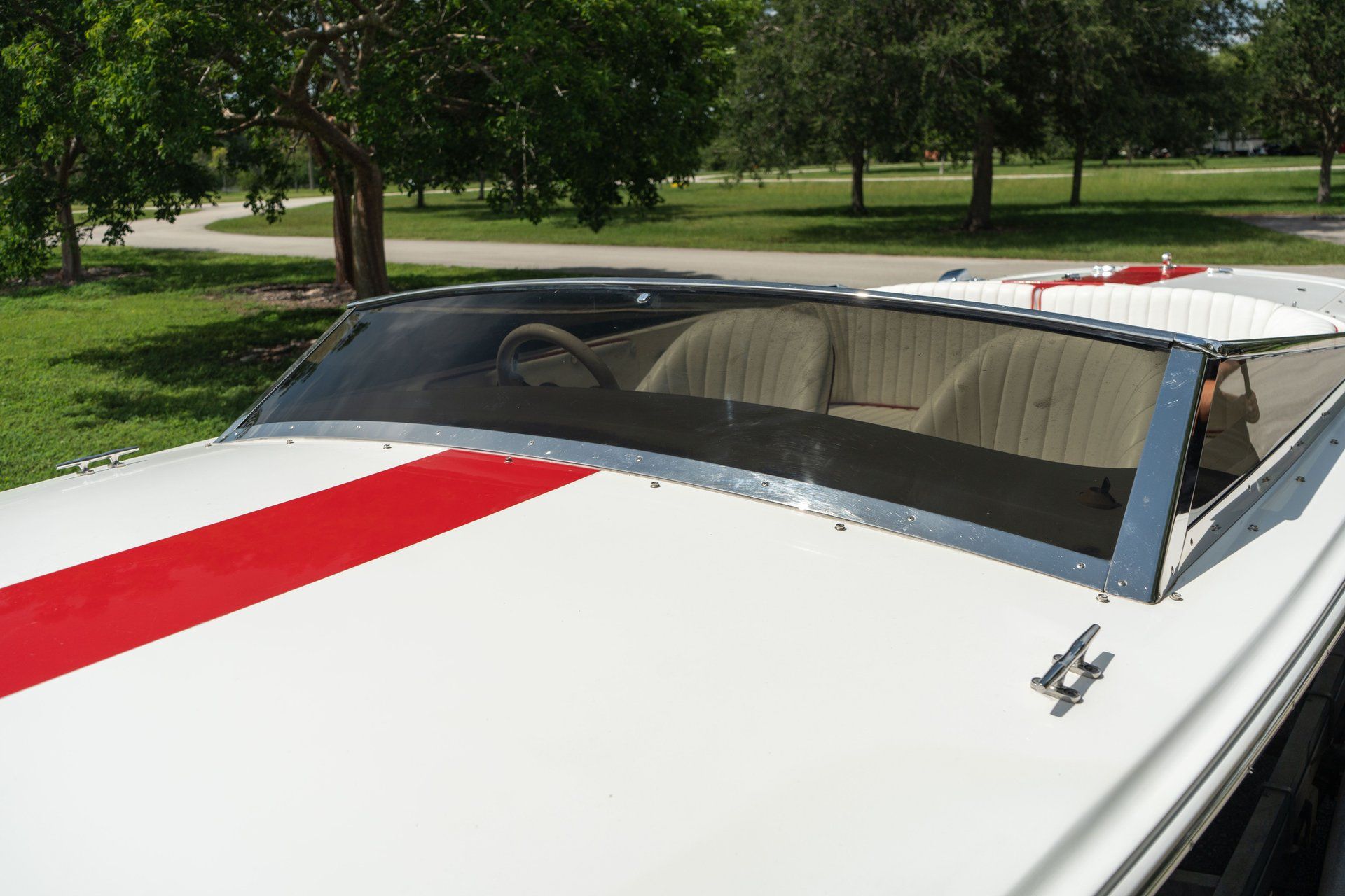 A 1995 Donzi Classic with a red stripe, parked in a green park.
