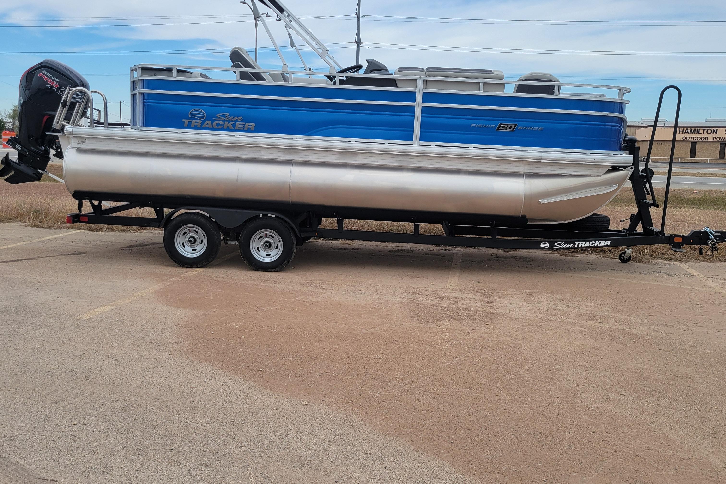 2026 Sun Tracker Fishin' Barge 20 DLX pontoon boat on trailer, parked outdoors.