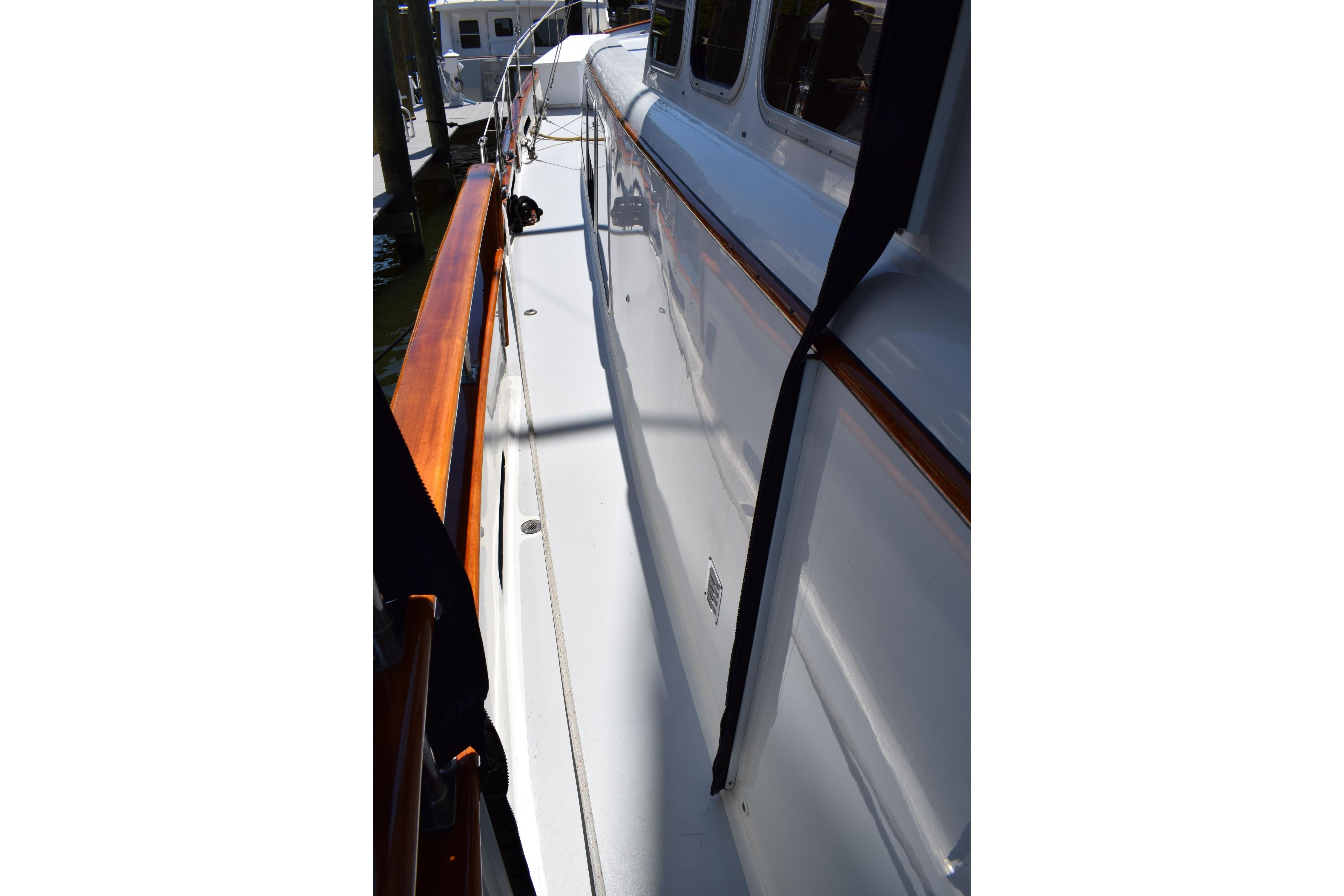1980 Cheoy Lee 52 Motorsailer deck with polished wood railing and white surface.