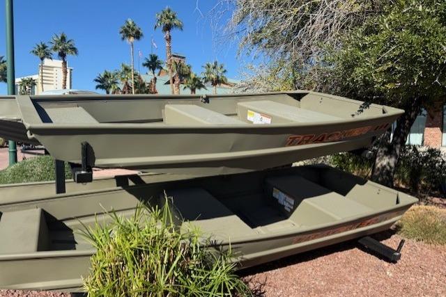 2026 Tracker Grizzly 10 Jon boats stacked outdoors, surrounded by palm trees and greenery.