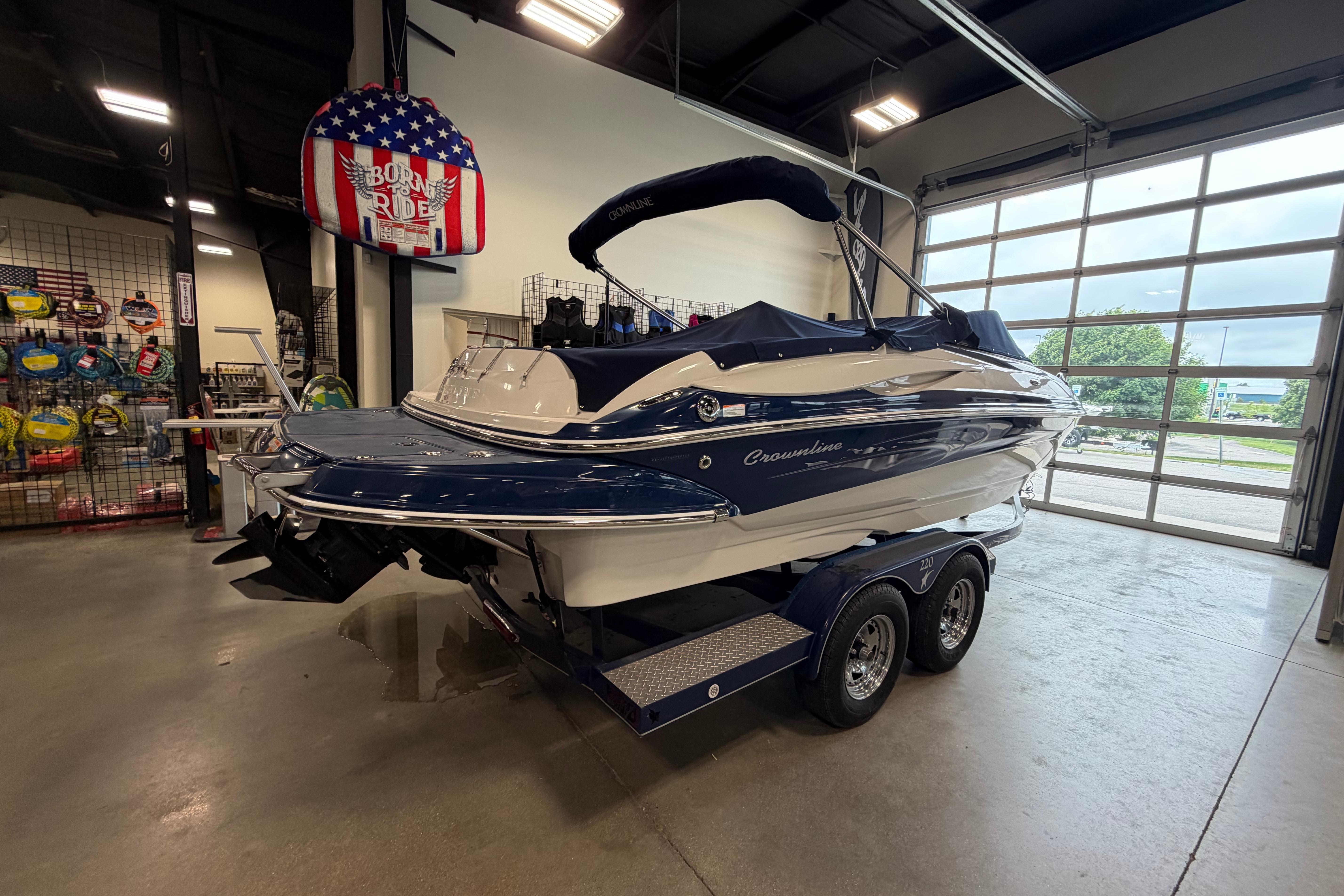 2008 Crownline 220 LS boat on trailer in showroom, featuring sleek design and blue accents.