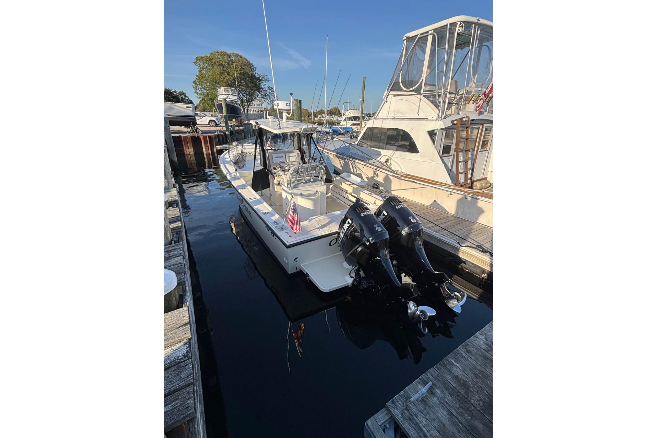 1999 Parker 2501 Center Console boat docked with twin outboard engines.