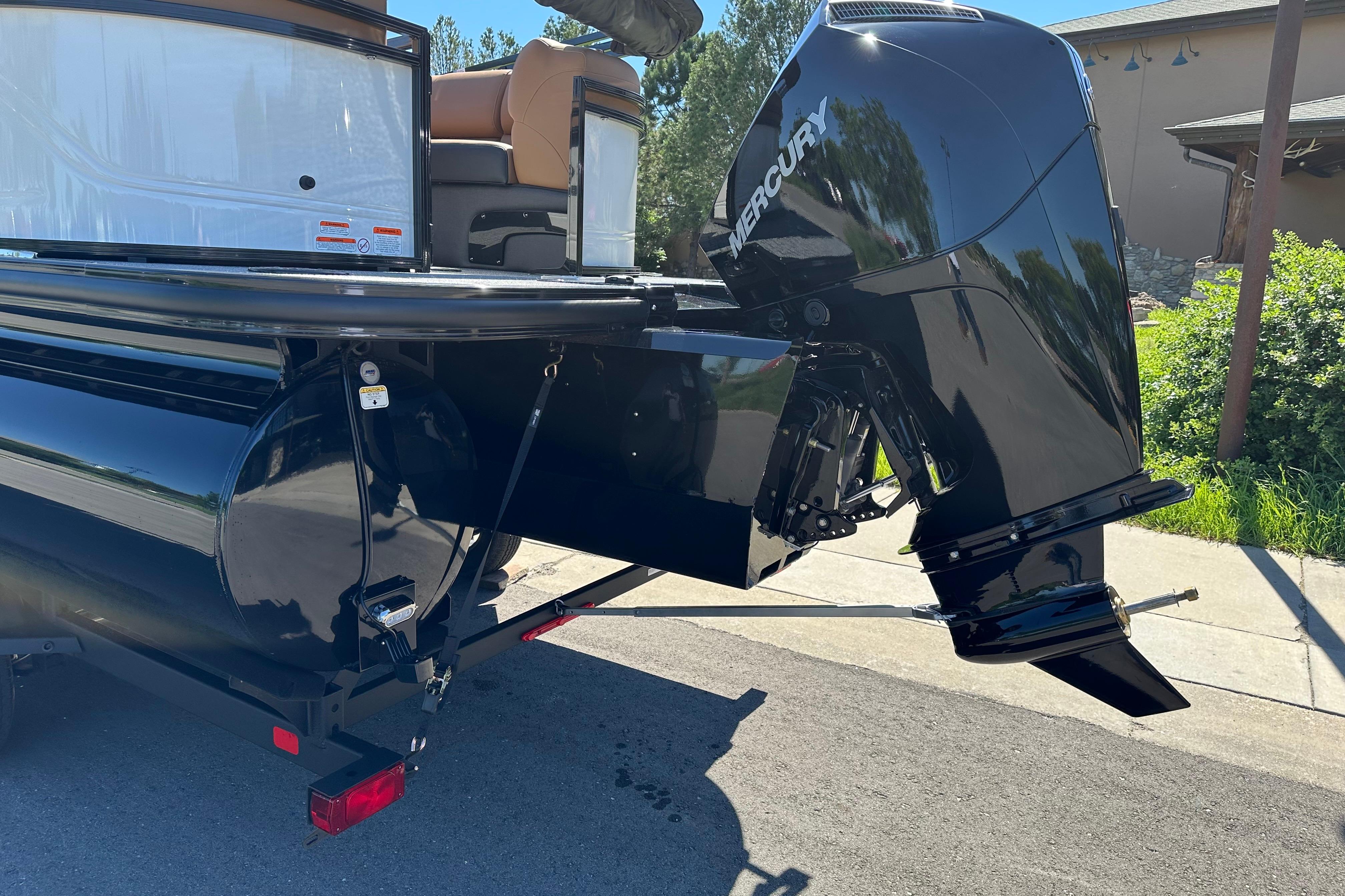 2026 Regency 230 DL boat with Mercury outboard motor, parked on a sunny day.