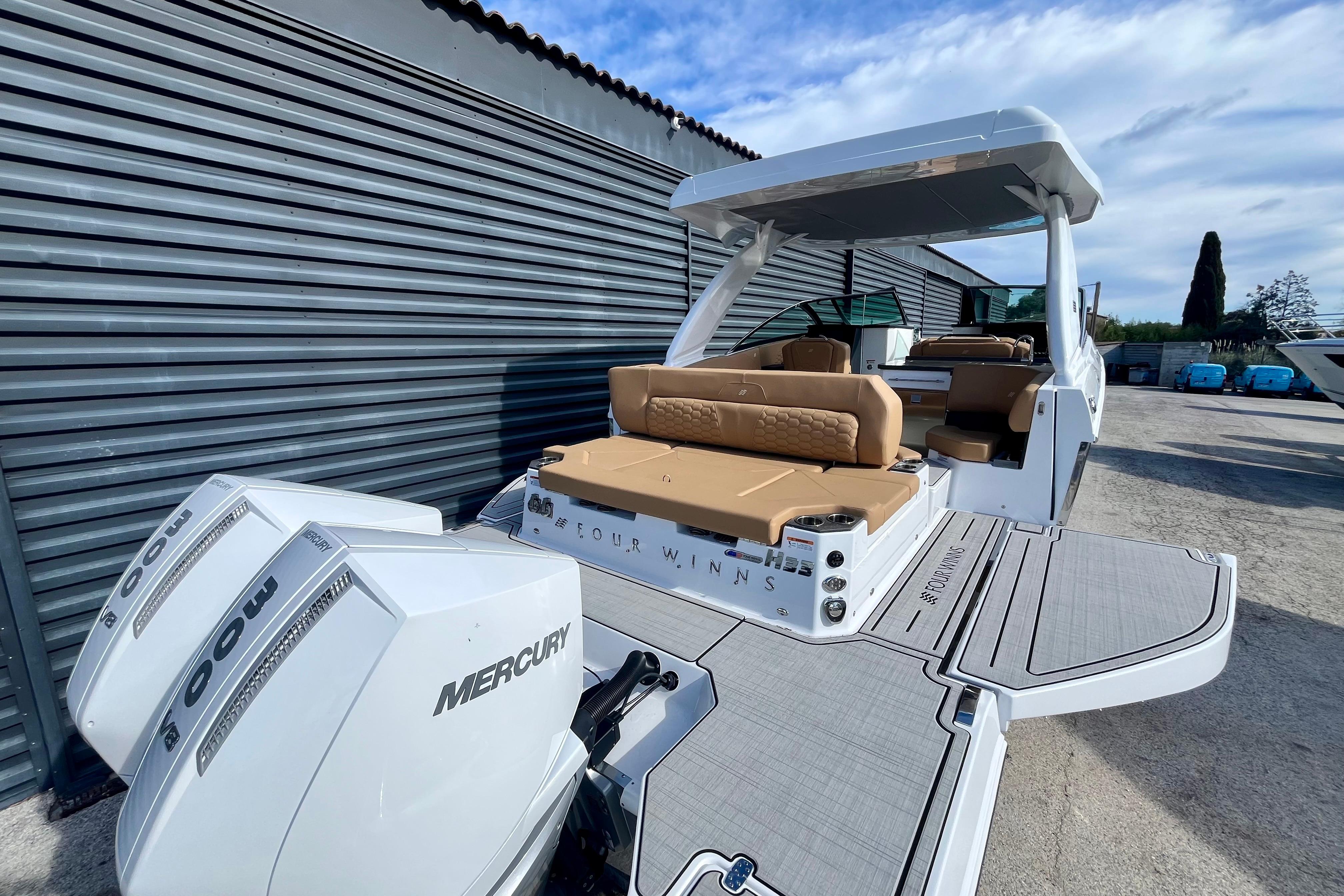 2026 Four Winns H33 OB boat with twin Mercury outboard engines, docked outdoors.