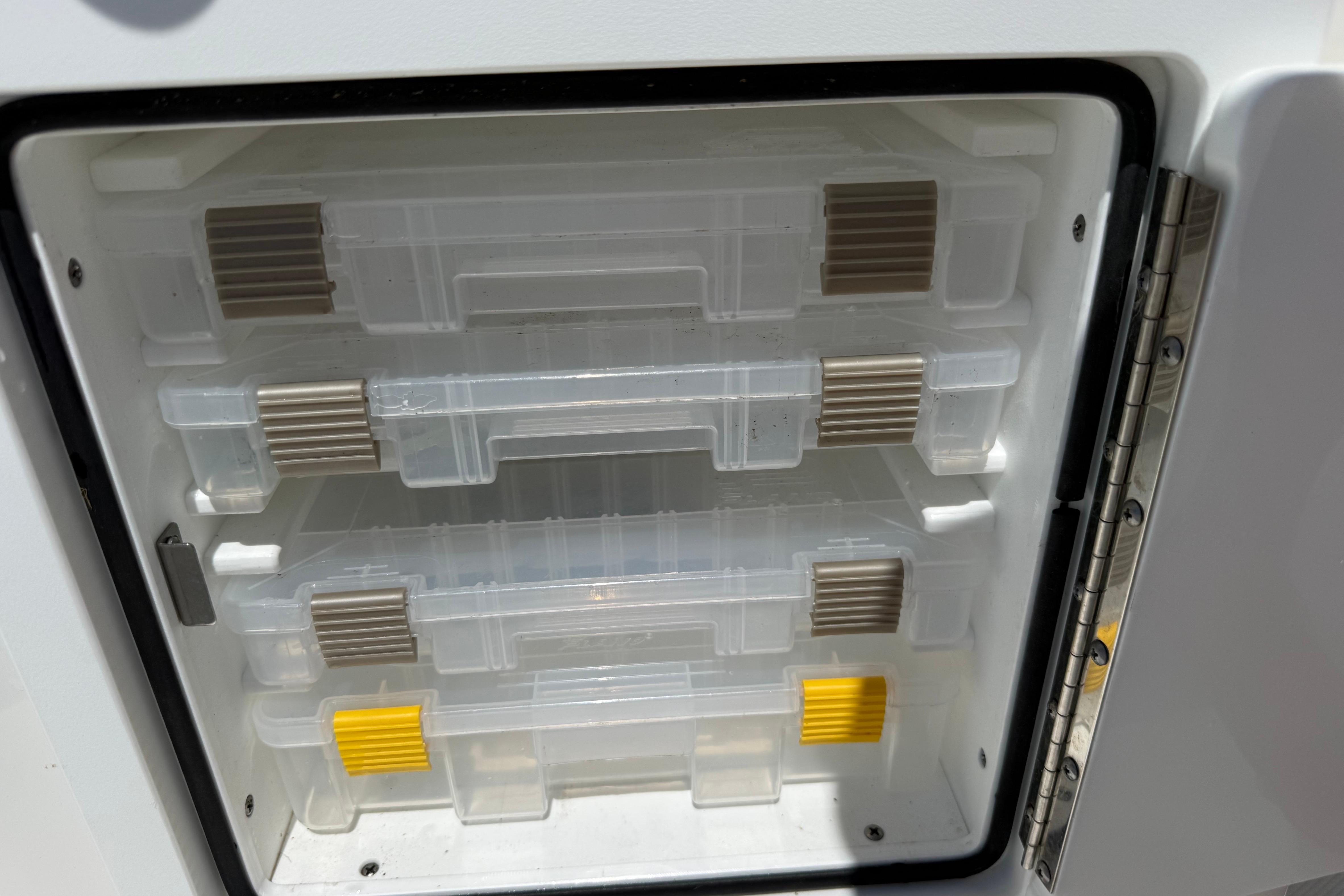 Storage compartment with clear plastic trays in a 2023 Regulator 26XO boat.