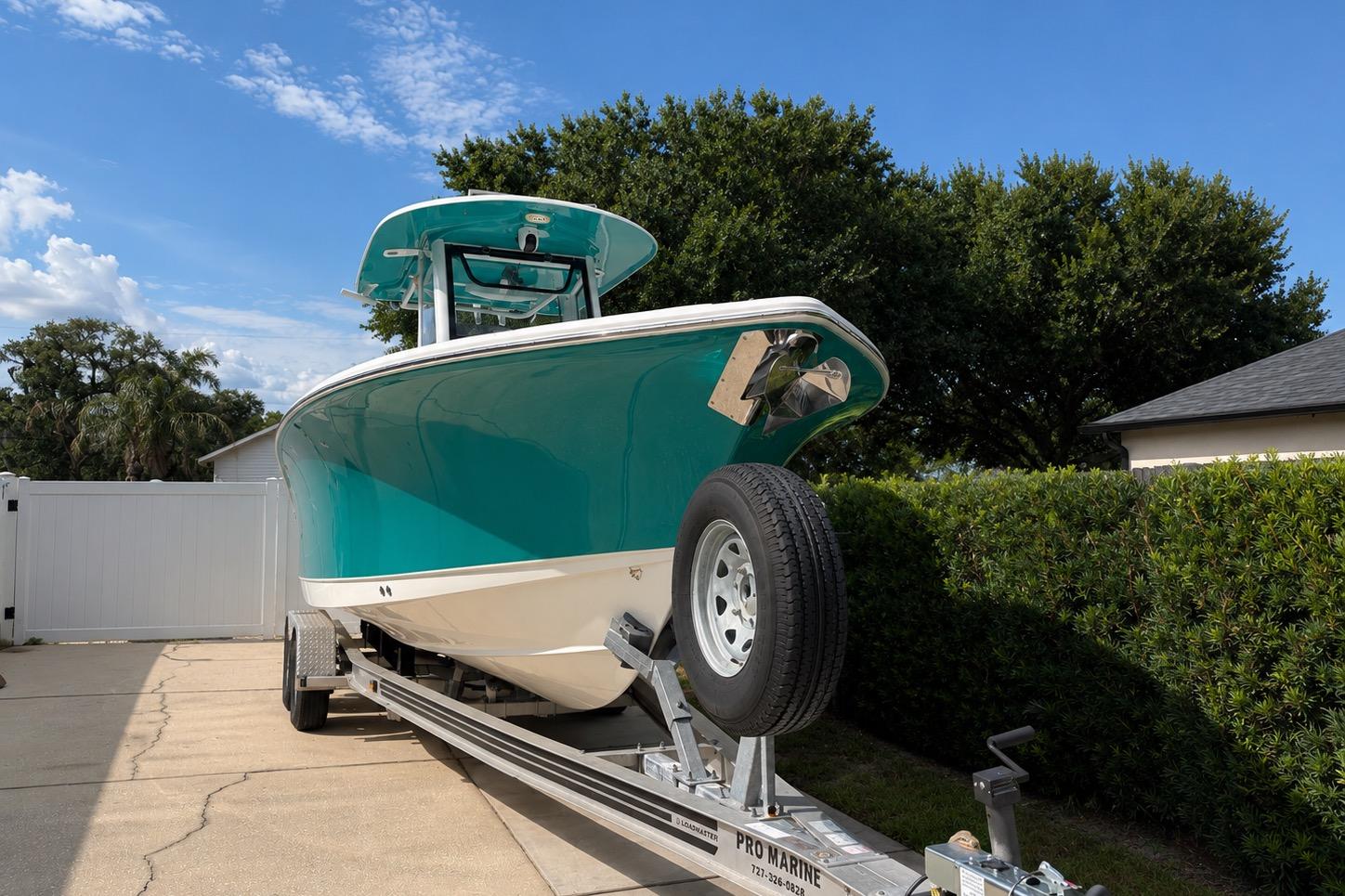 2021 Sea Hunt Ultra 265 SE boat on trailer, parked in driveway with lush greenery.