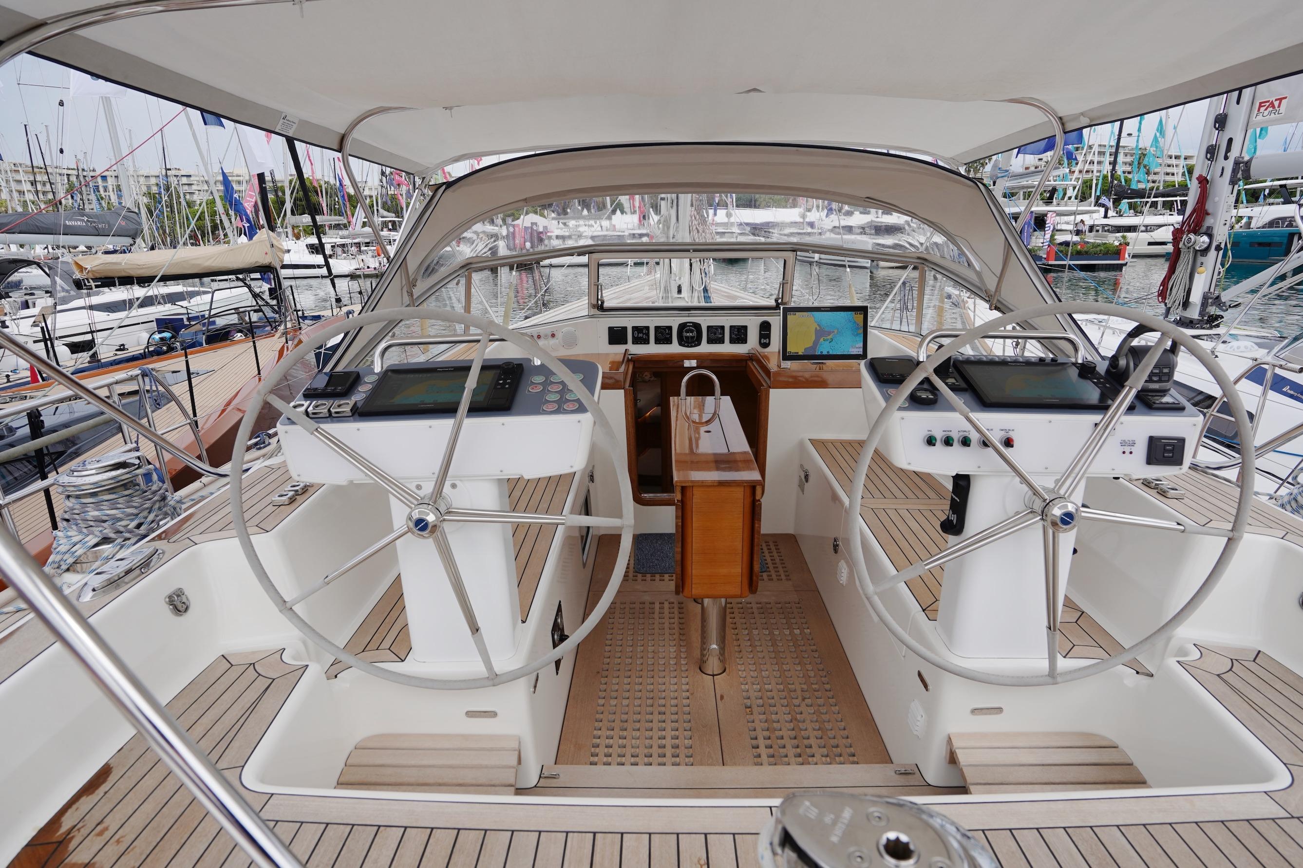 Luxurious 2022 Hallberg-Rassy 57 yacht cockpit with dual steering wheels and navigation equipment.