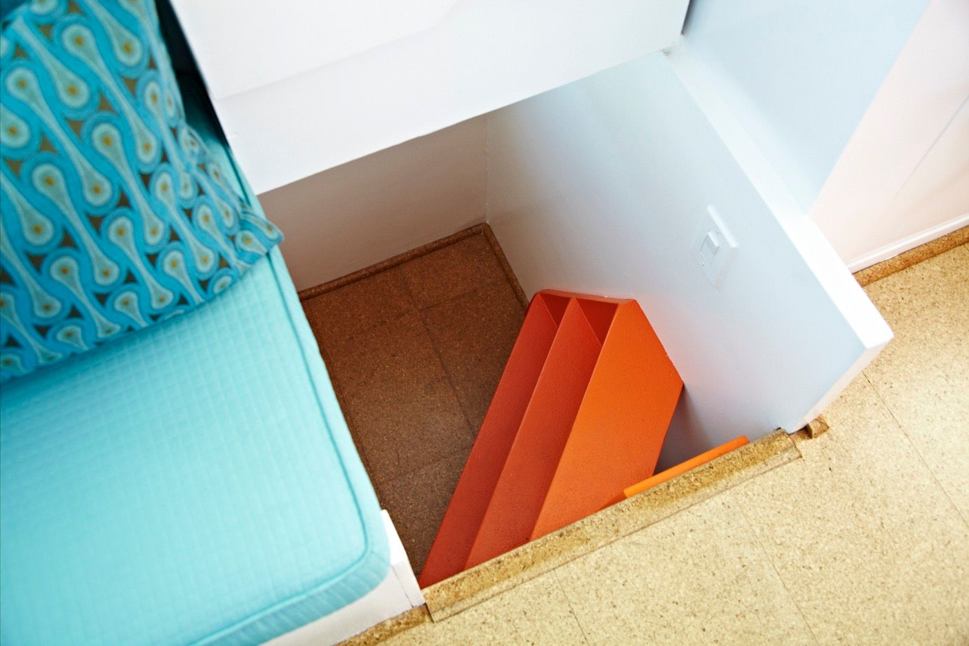 Interior of a houseboat with orange stairs and a turquoise seat.
