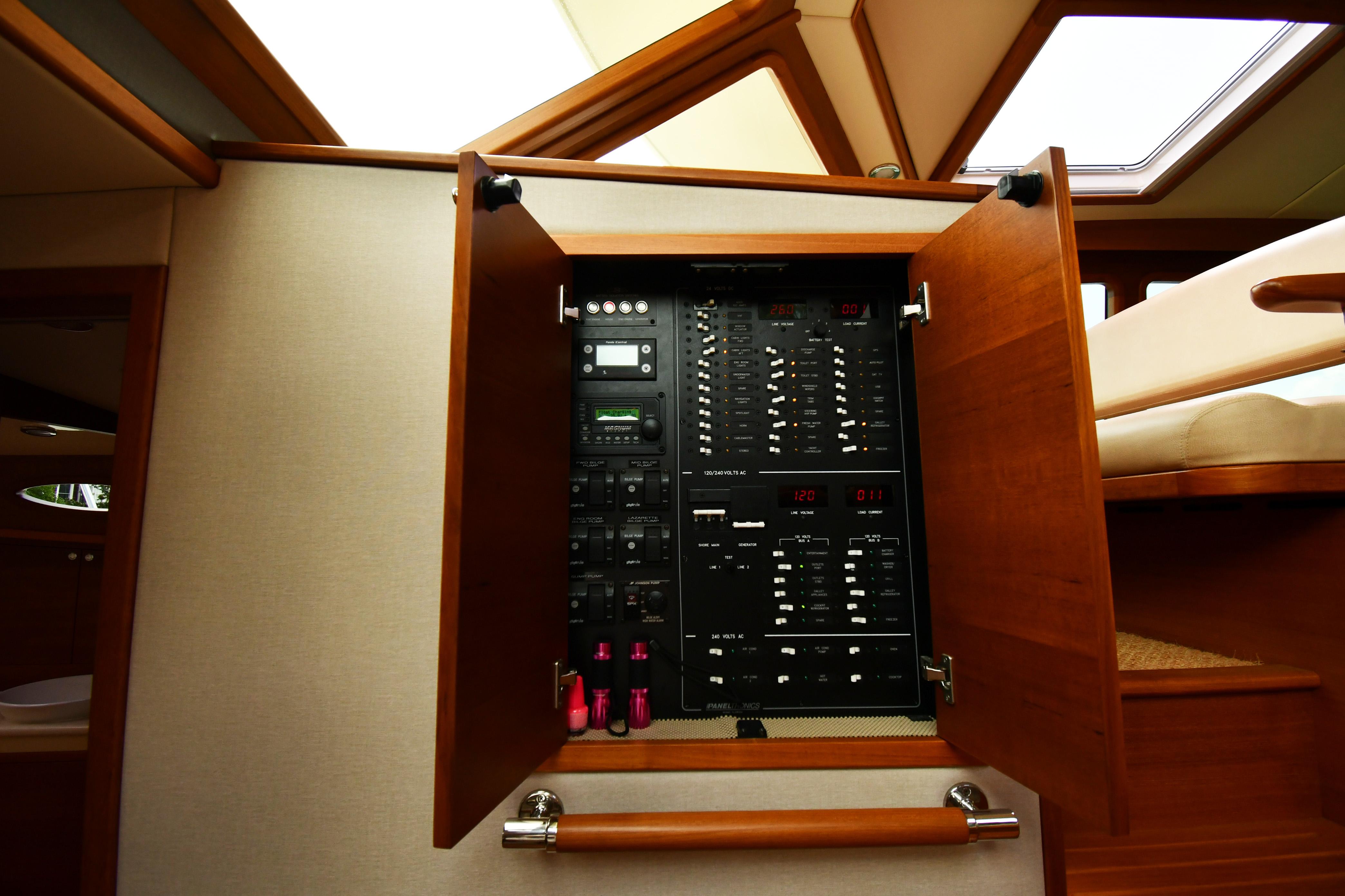 Electrical panel inside 2020 Palm Beach Motor Yachts PB52, showcasing control systems and wooden cabinetry.