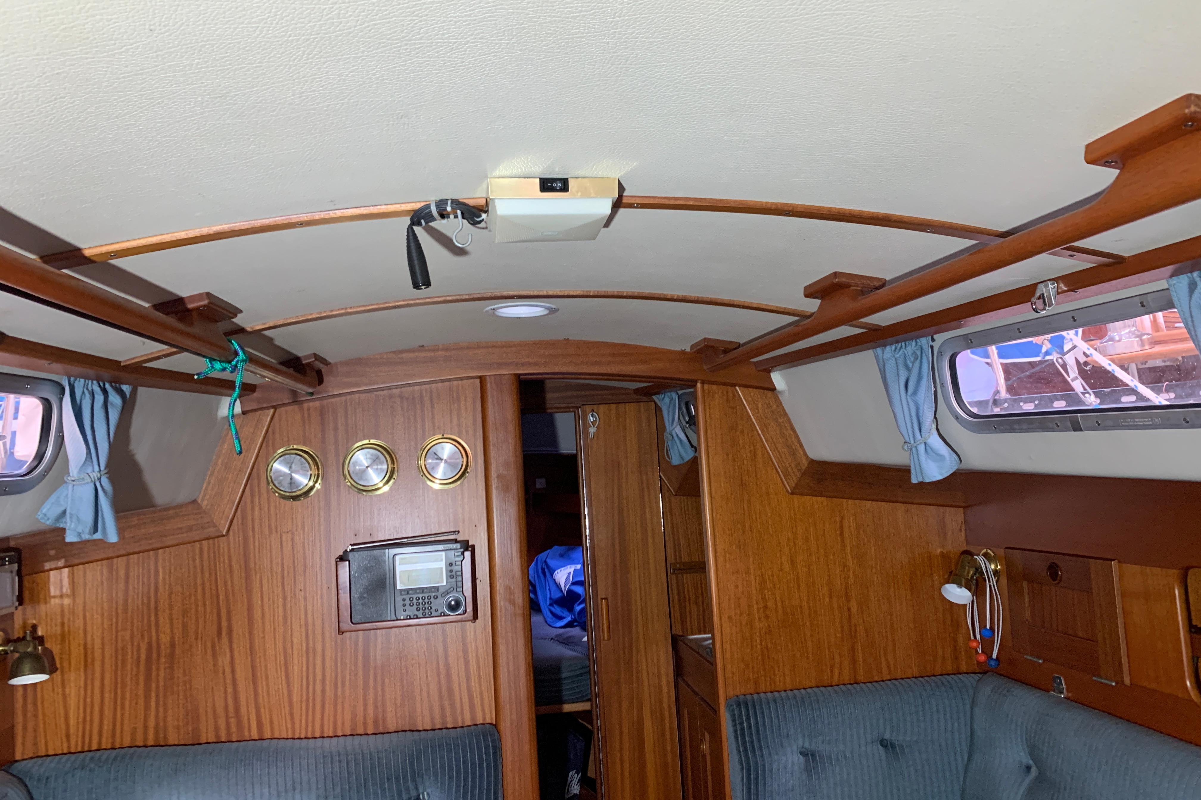 Interior of a 1990 Hallberg-Rassy 29 sailboat with wood paneling and nautical instruments.