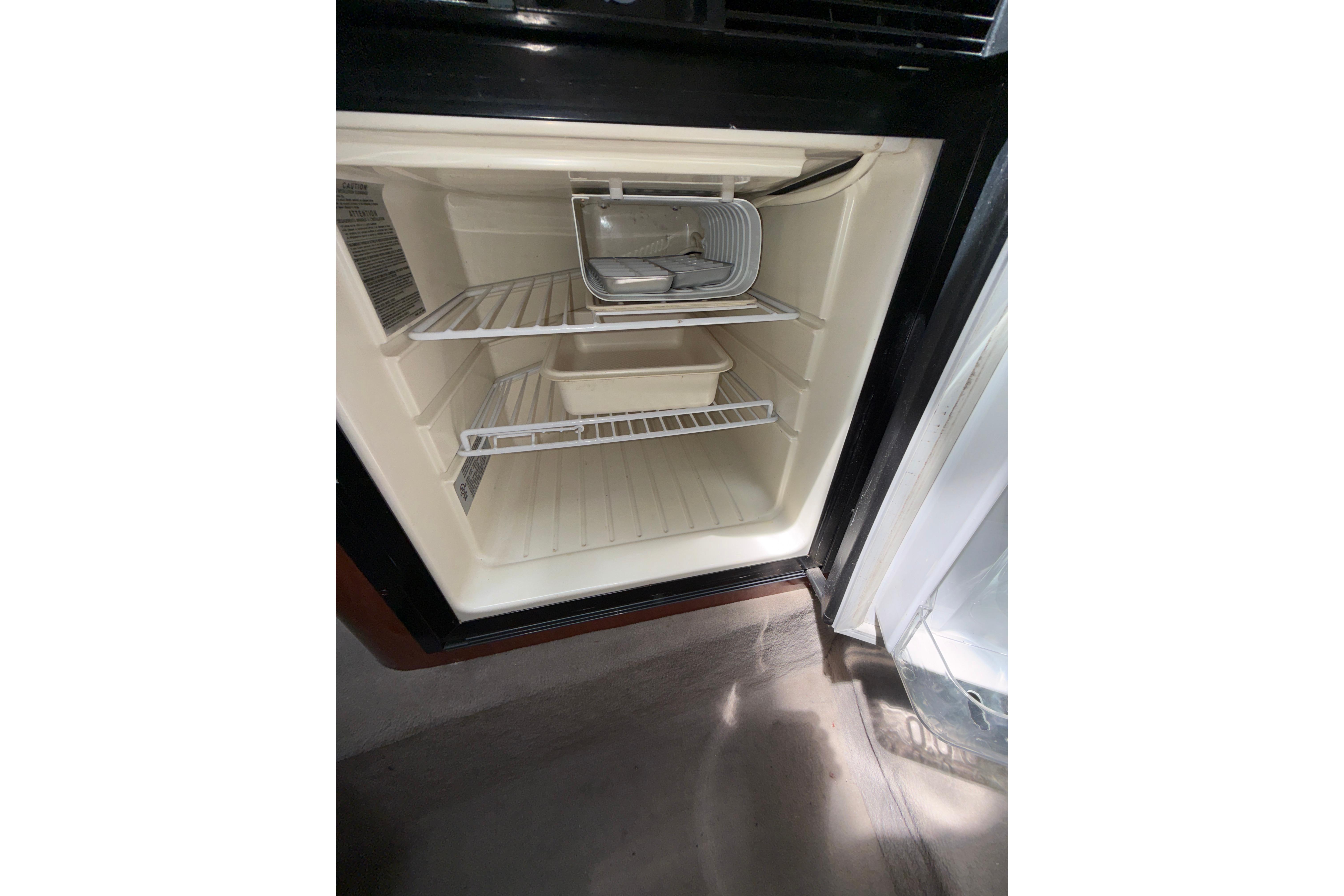 Empty refrigerator inside a 2004 Sea Ray 240 Sundancer boat, showing shelves and compartments.
