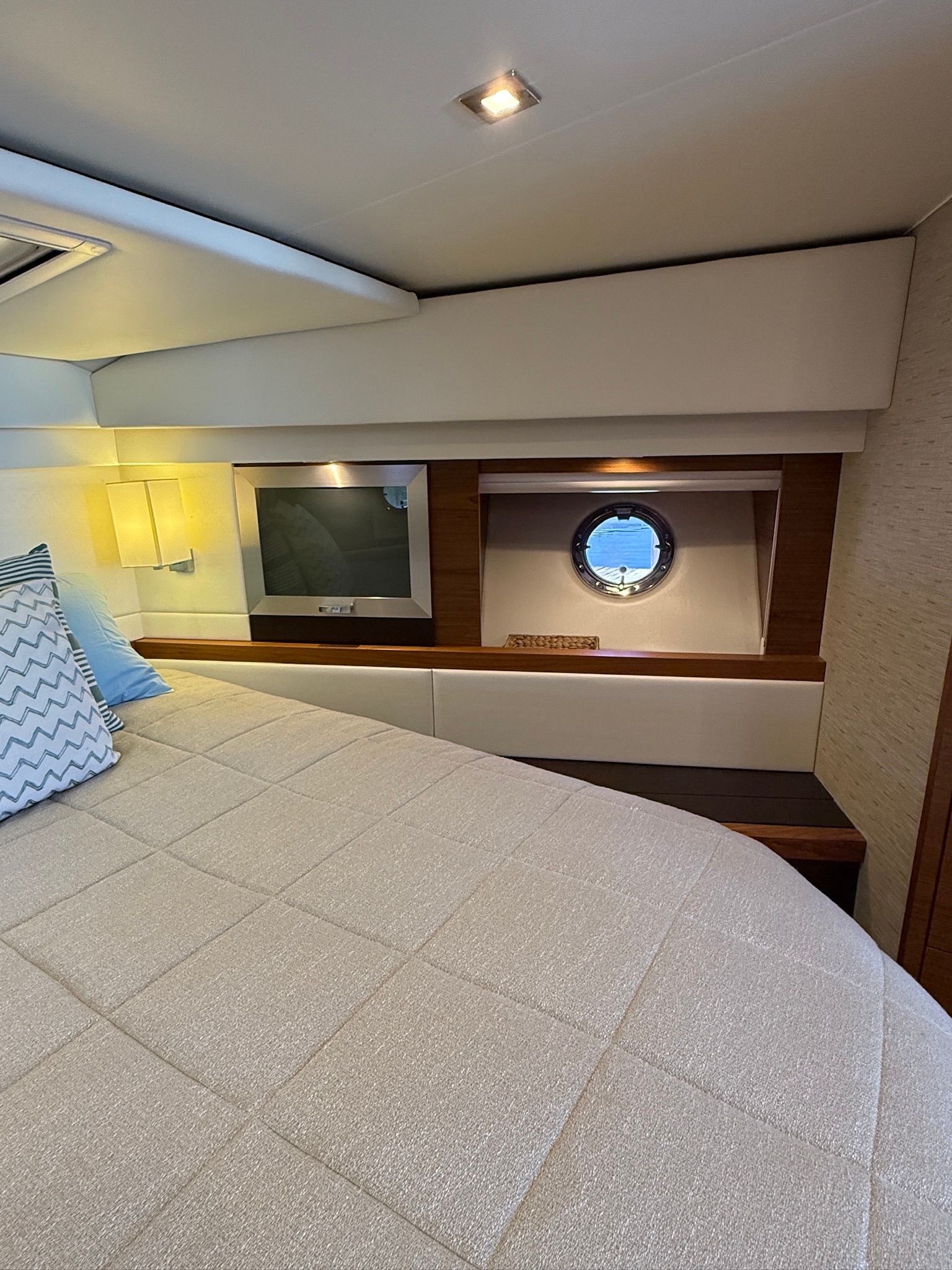 Interior of a 2017 Tiara Yachts C44 Coupe with a cozy bed and porthole.