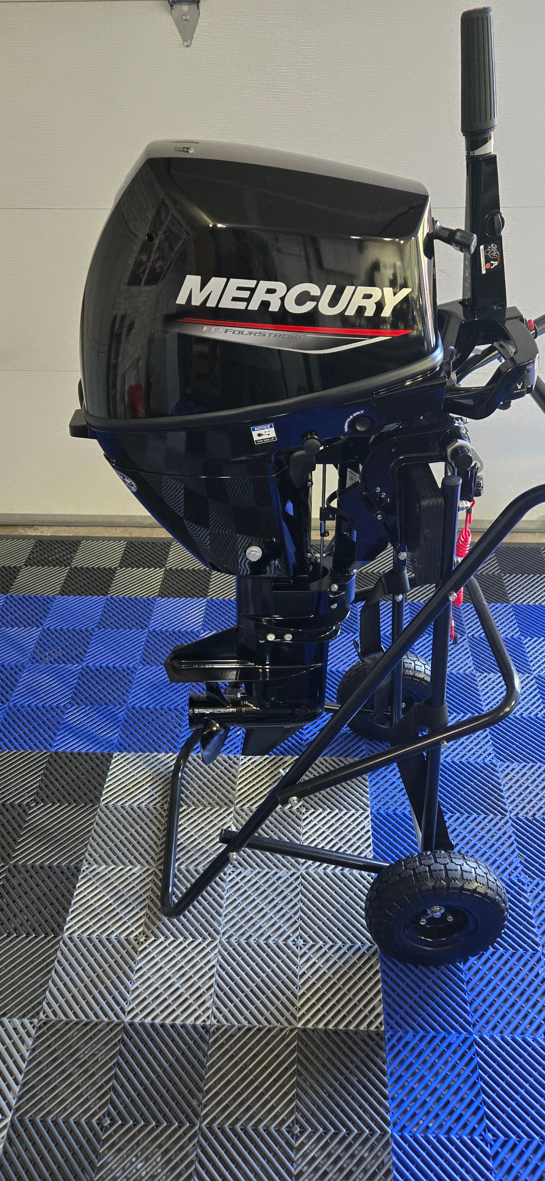 A Mercury outboard motor on a blue and gray floor.