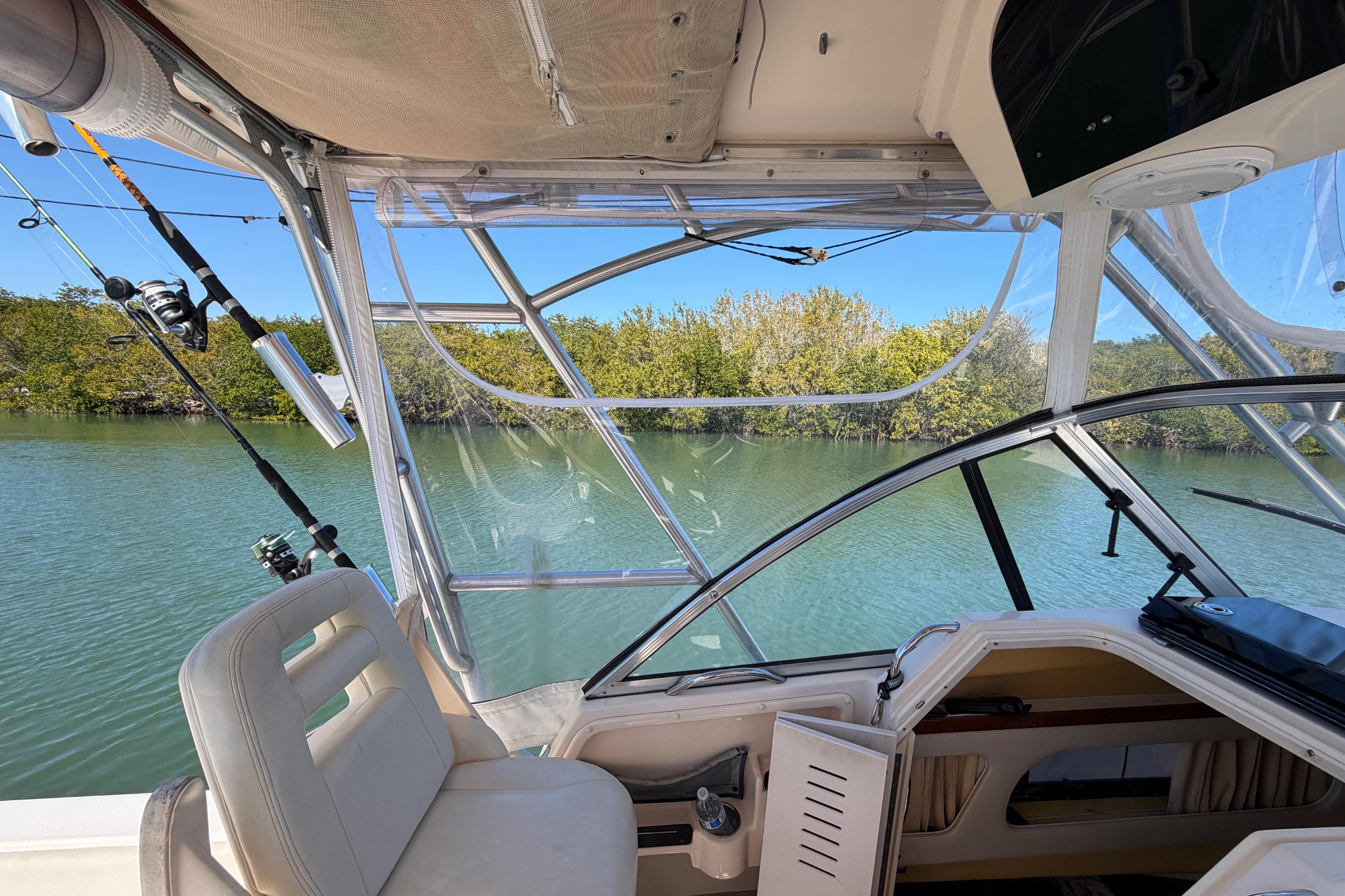 2006 Grady-White Sailfish 282 boat interior with fishing rods, calm water, and lush greenery.