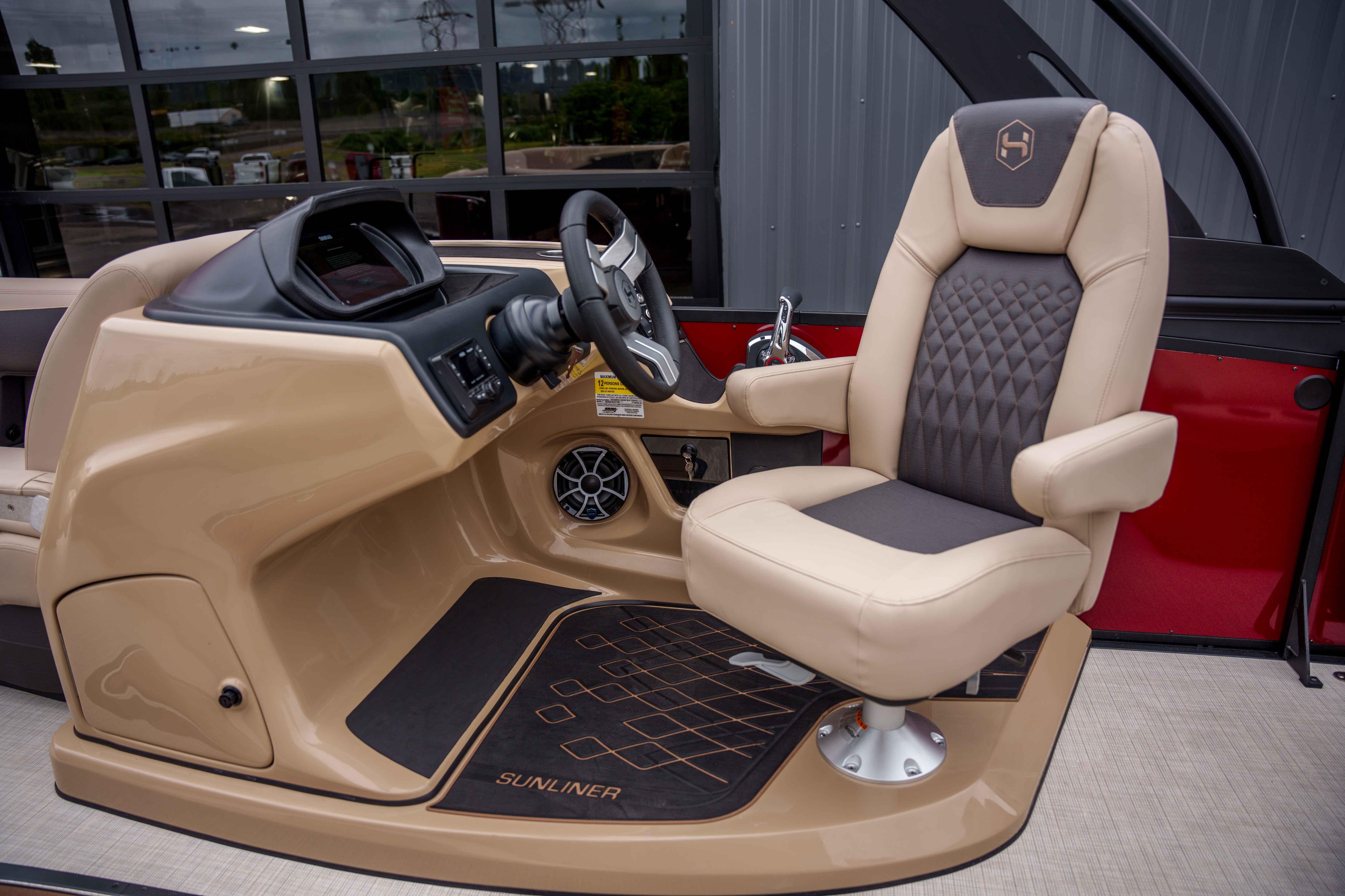 Captain's chair and helm of 2026 Harris Sunliner 230 boat, featuring modern design and controls.