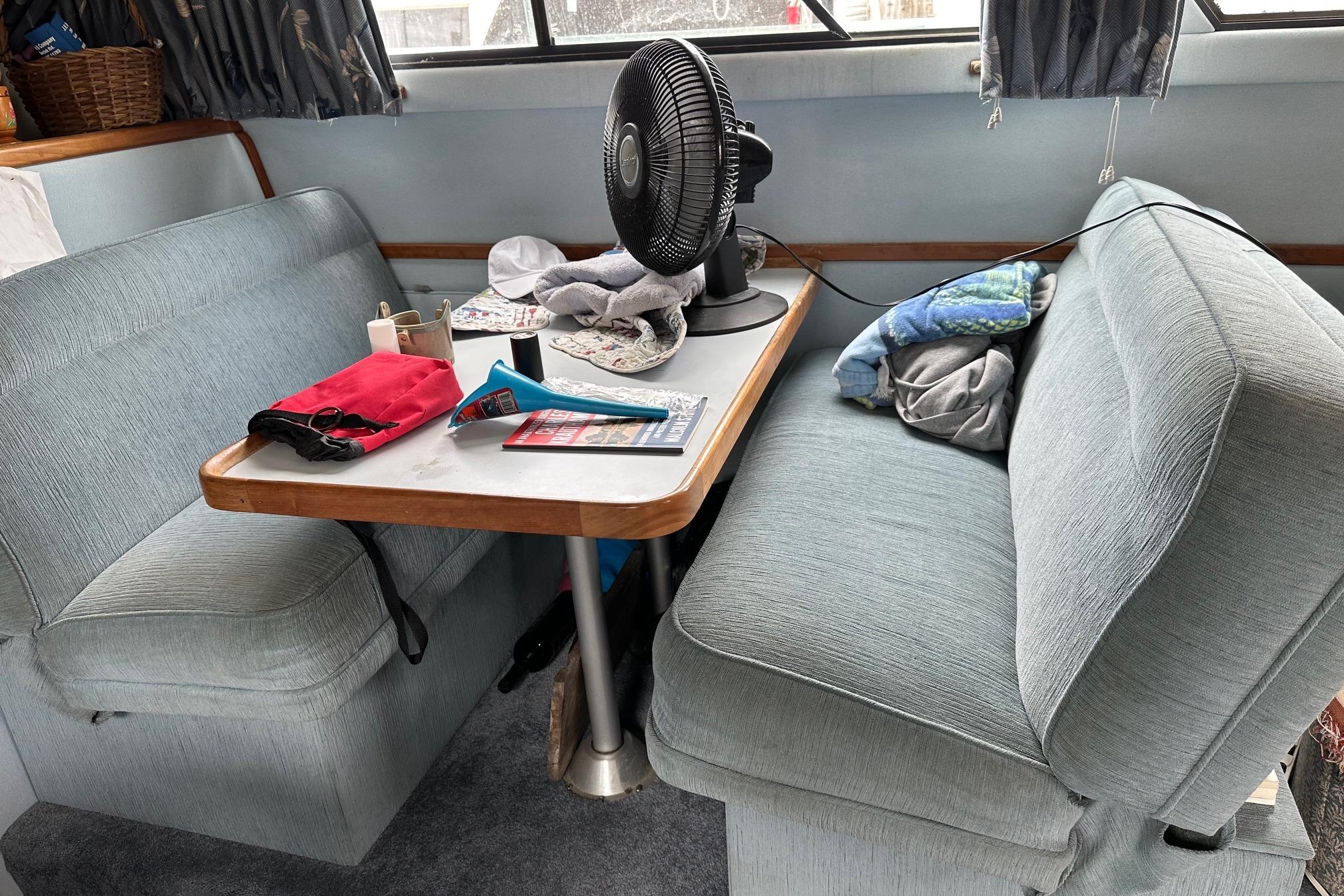 Cozy dining area inside a 1989 Sea Ray 380 Aft Cabin yacht with fan and seating.
