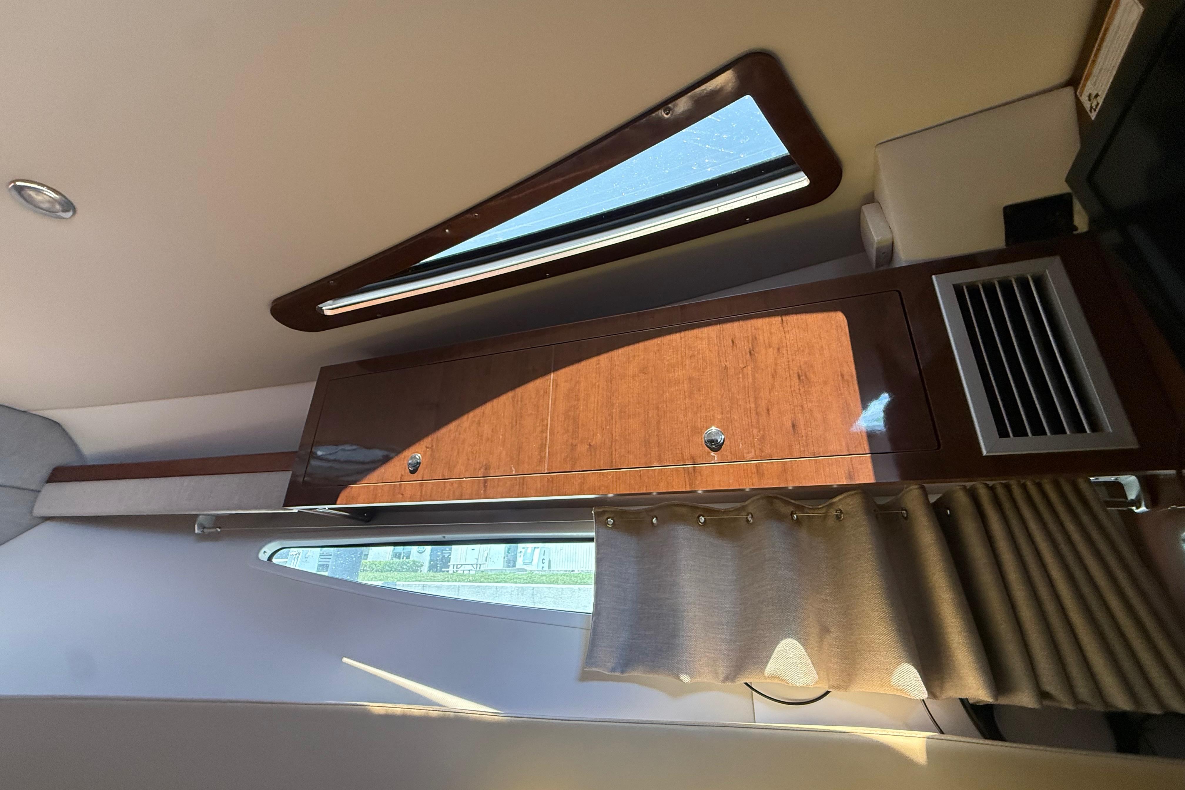 Interior of 2017 Four Winns V275 boat with wooden cabinet and window.
