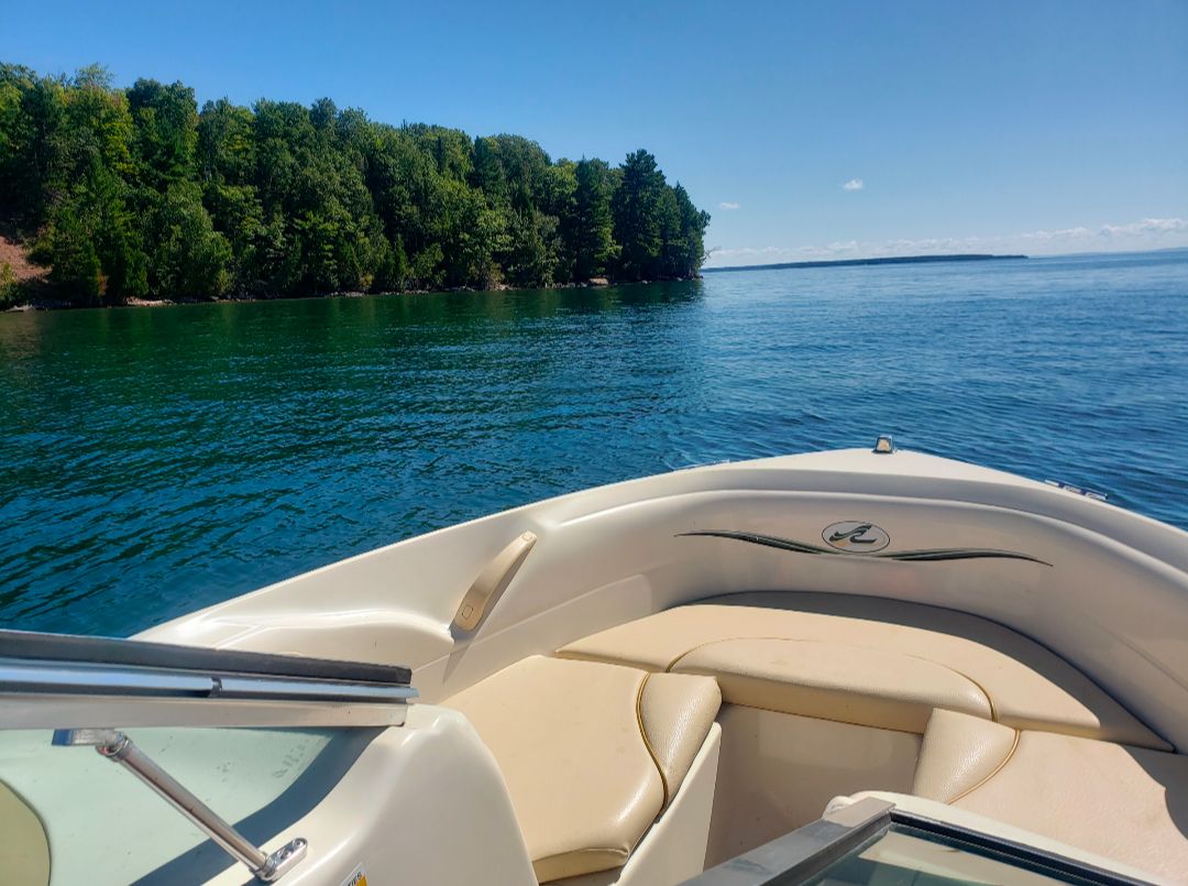 A boat on a calm lake with a wooded shoreline in the background.