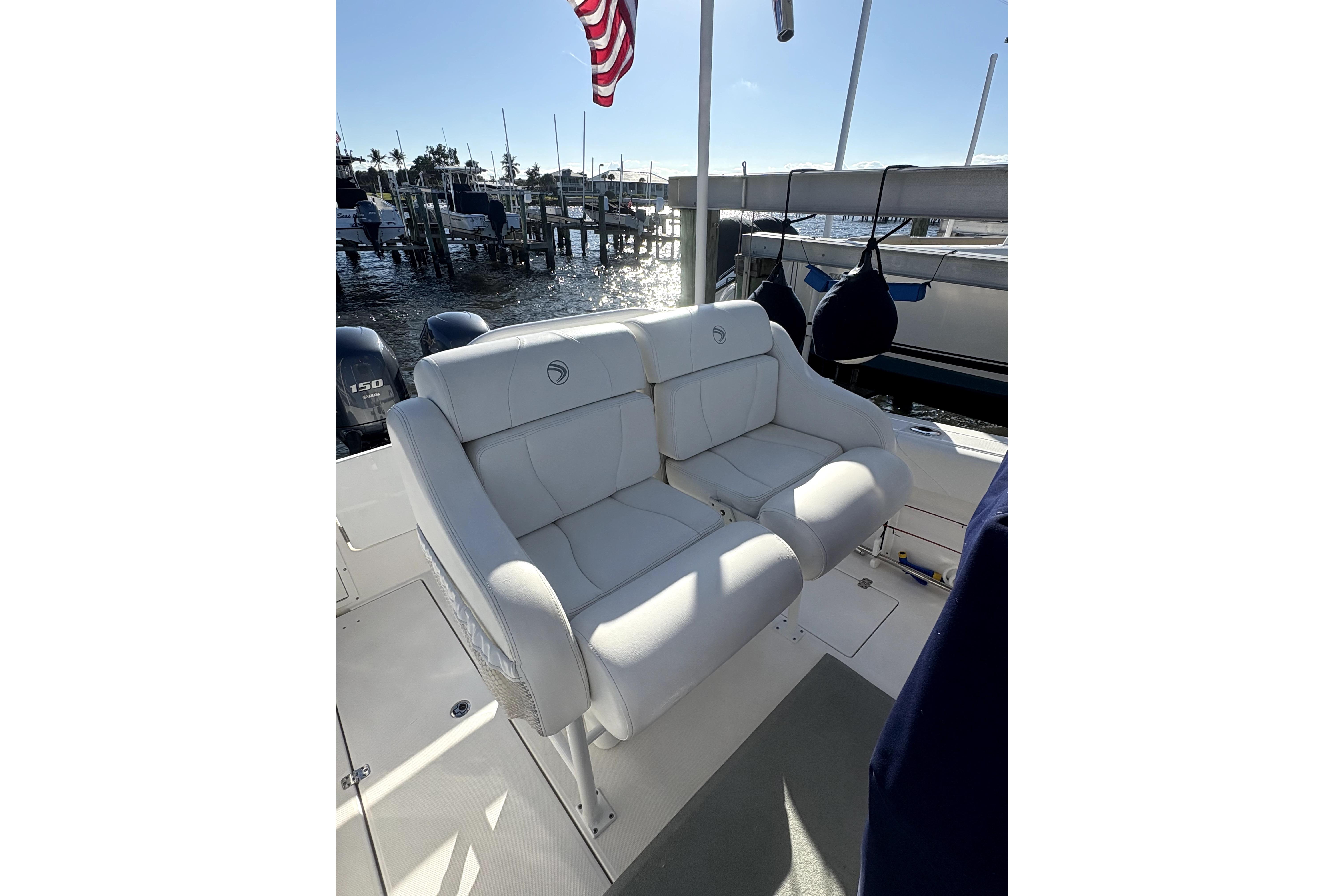 2015 Edgewater 245CC boat with white cushioned seating, docked near water.
