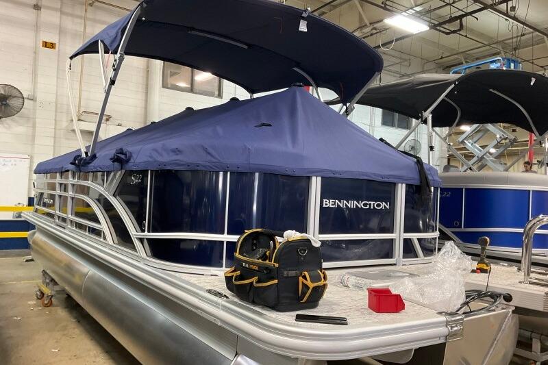 2026 Bennington 23 SSRSF pontoon boat in a workshop with blue cover.