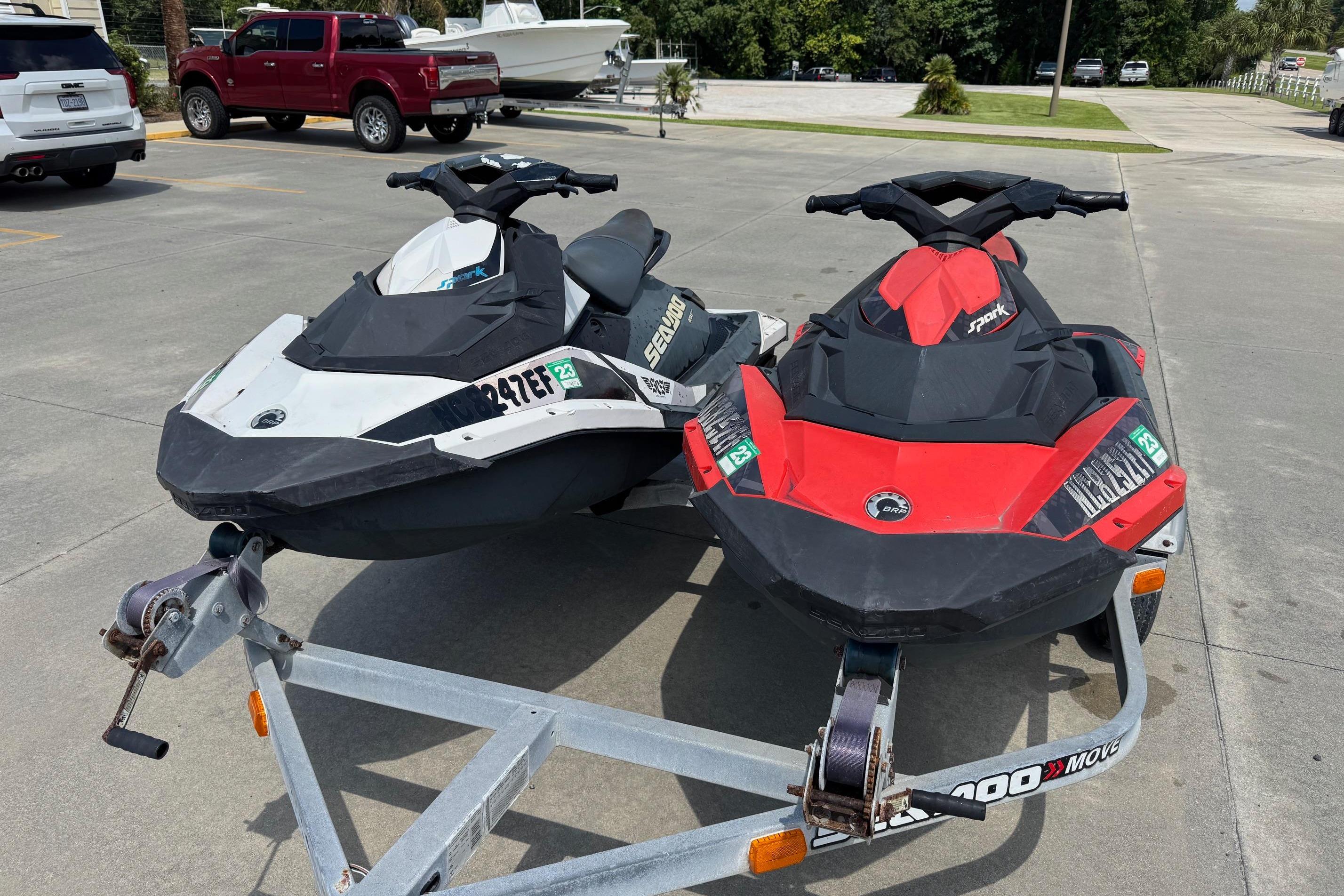 Two 2017 Sea-Doo Spark 2up jet skis on a trailer in a parking lot.