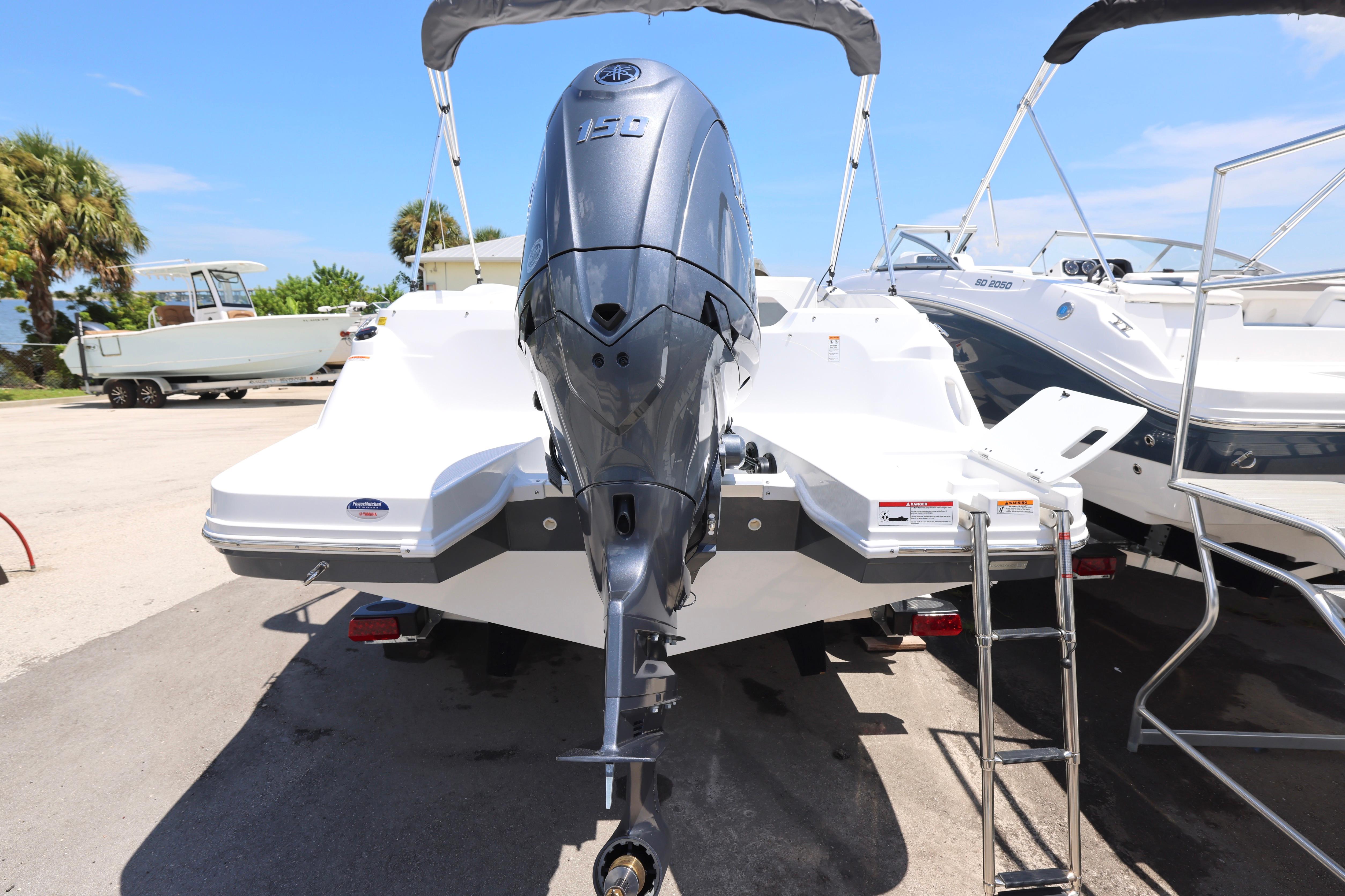 2026 Hurricane SunDeck Sport 205 OB boat with powerful outboard motor, parked outdoors.
