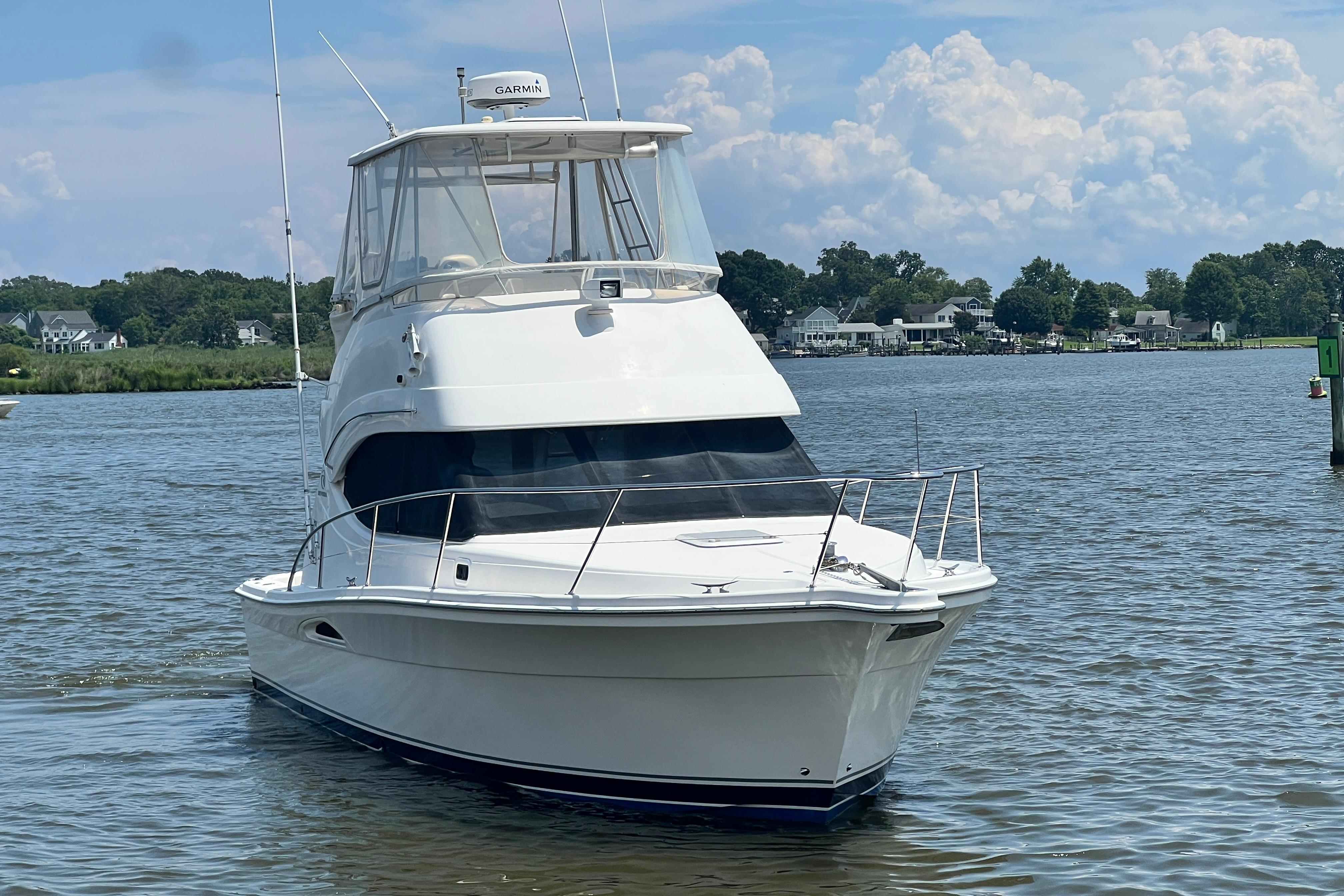 2007 Riviera 33 Flybridge yacht on calm water with scenic background.