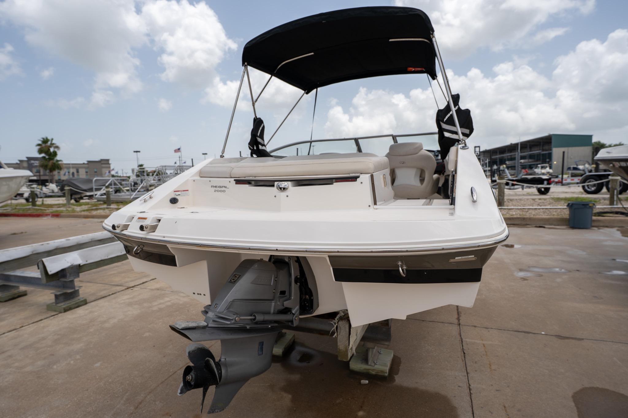 2008 Regal 2000 Bowrider boat with canopy, parked on a concrete surface under cloudy skies.